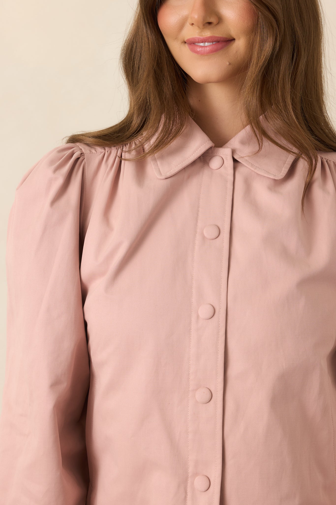 Close-up of the dusty pink jacket highlighting the pointed collar, snap closure, and softly gathered shoulder construction.