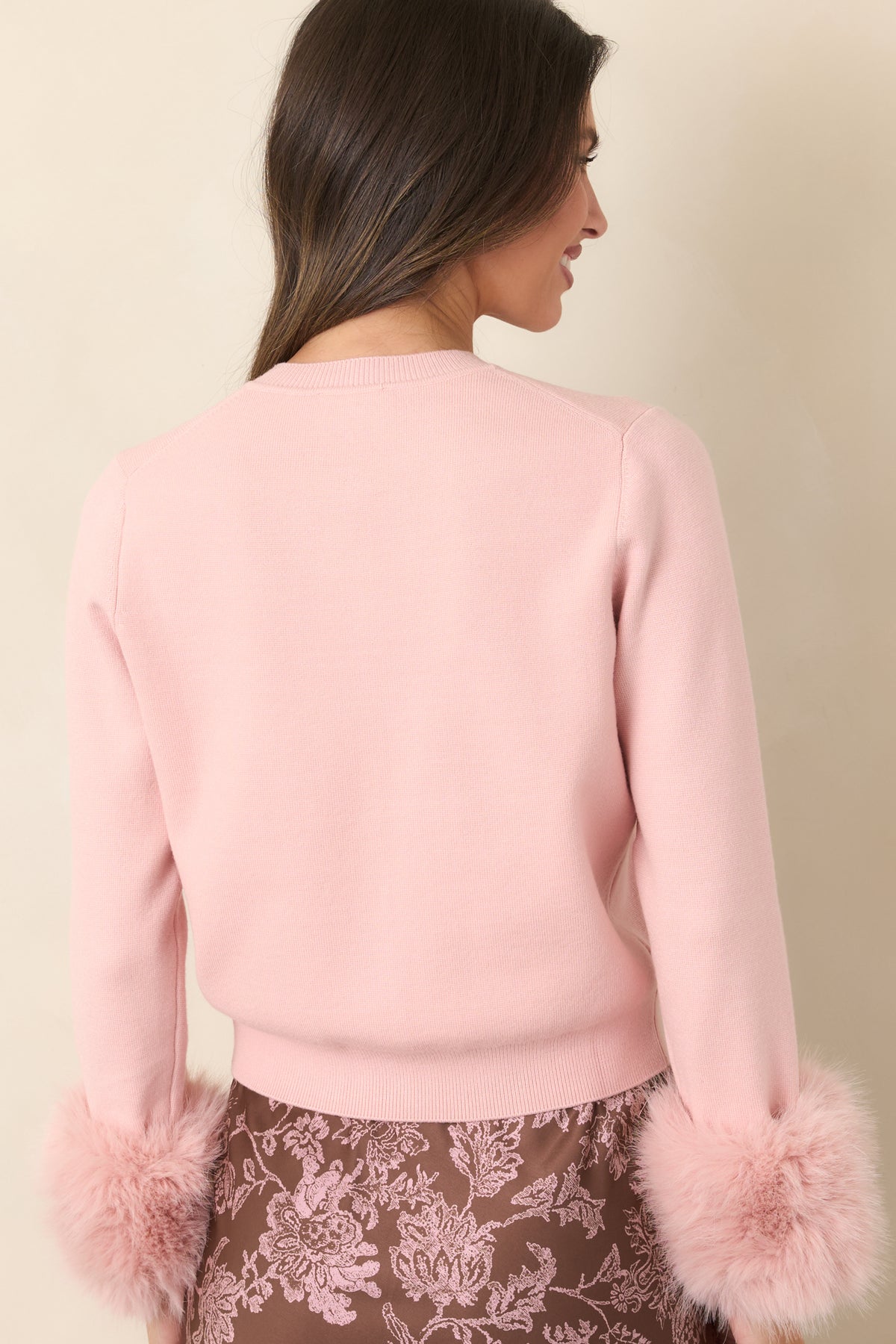 Dusty pink knit cardigan showcasing the classic silhouette, long sleeves, and neat hem from the rear.