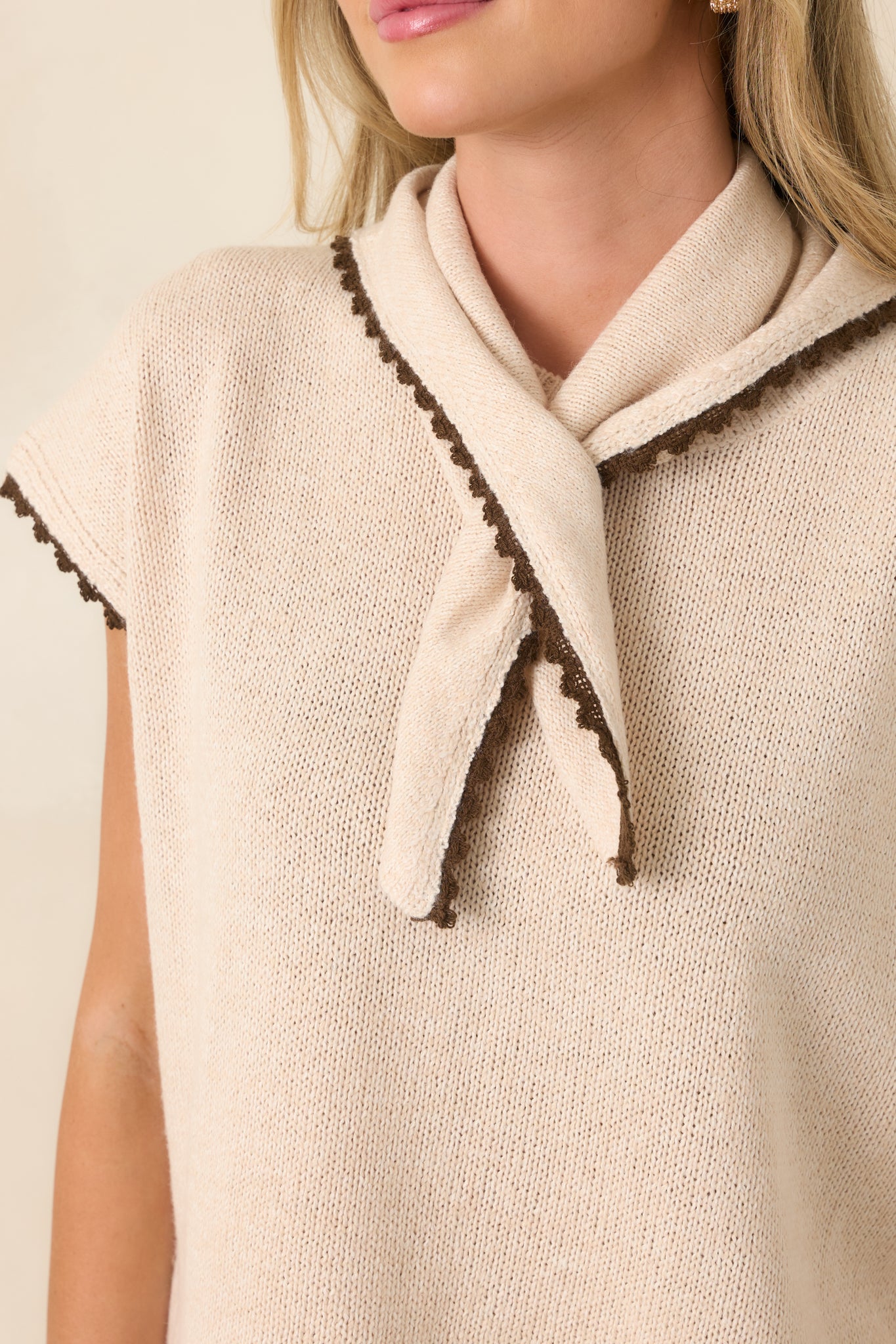 Close-up of the ecru cotton knit top highlighting the built-in scarf neckline, chocolate contrast trim, and textured knit finish.