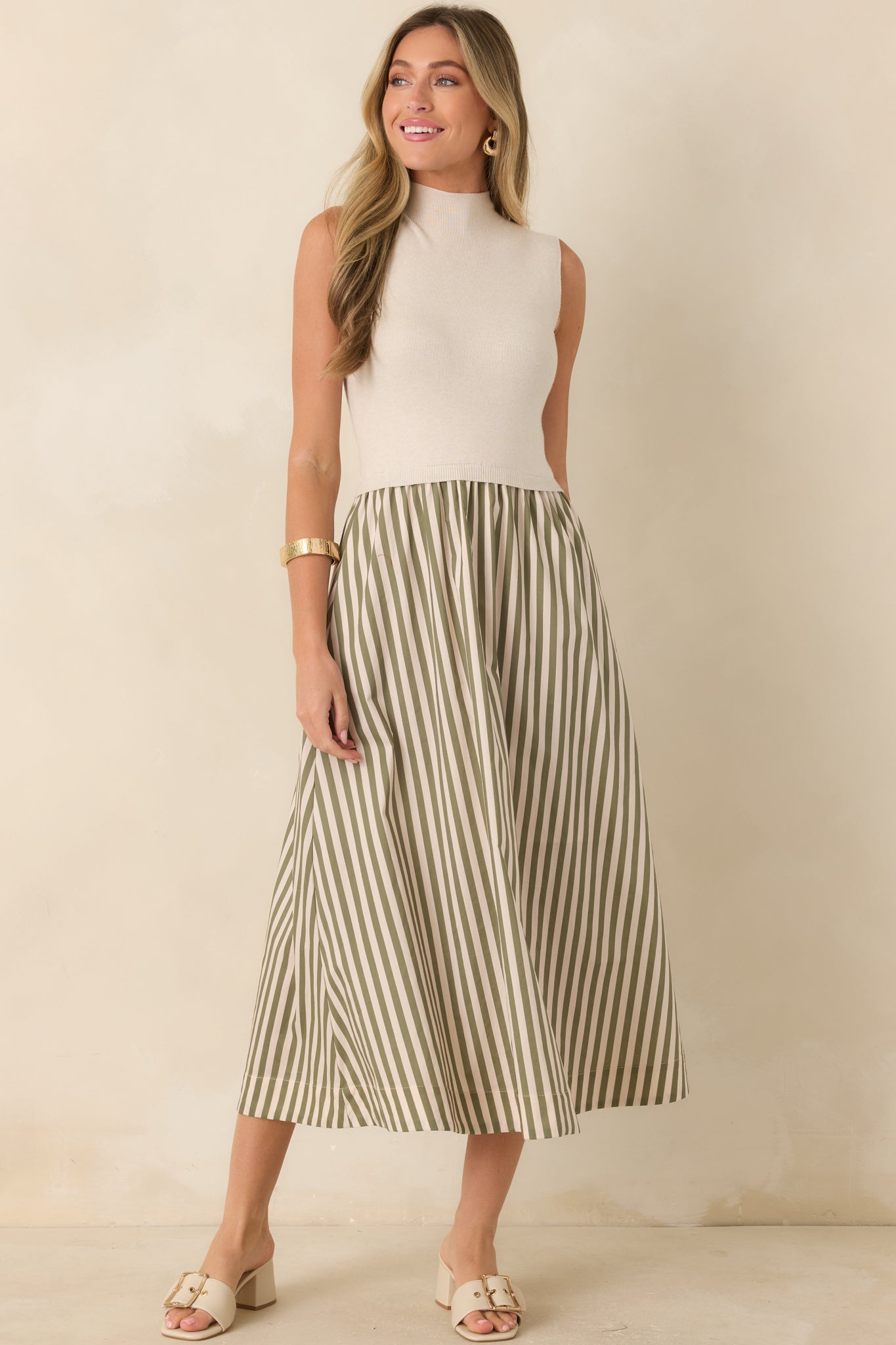 Ecru midi dress featuring a sleeveless silhouette, refined mock neckline, fitted knit bodice, and sage green striped A-line skirt.