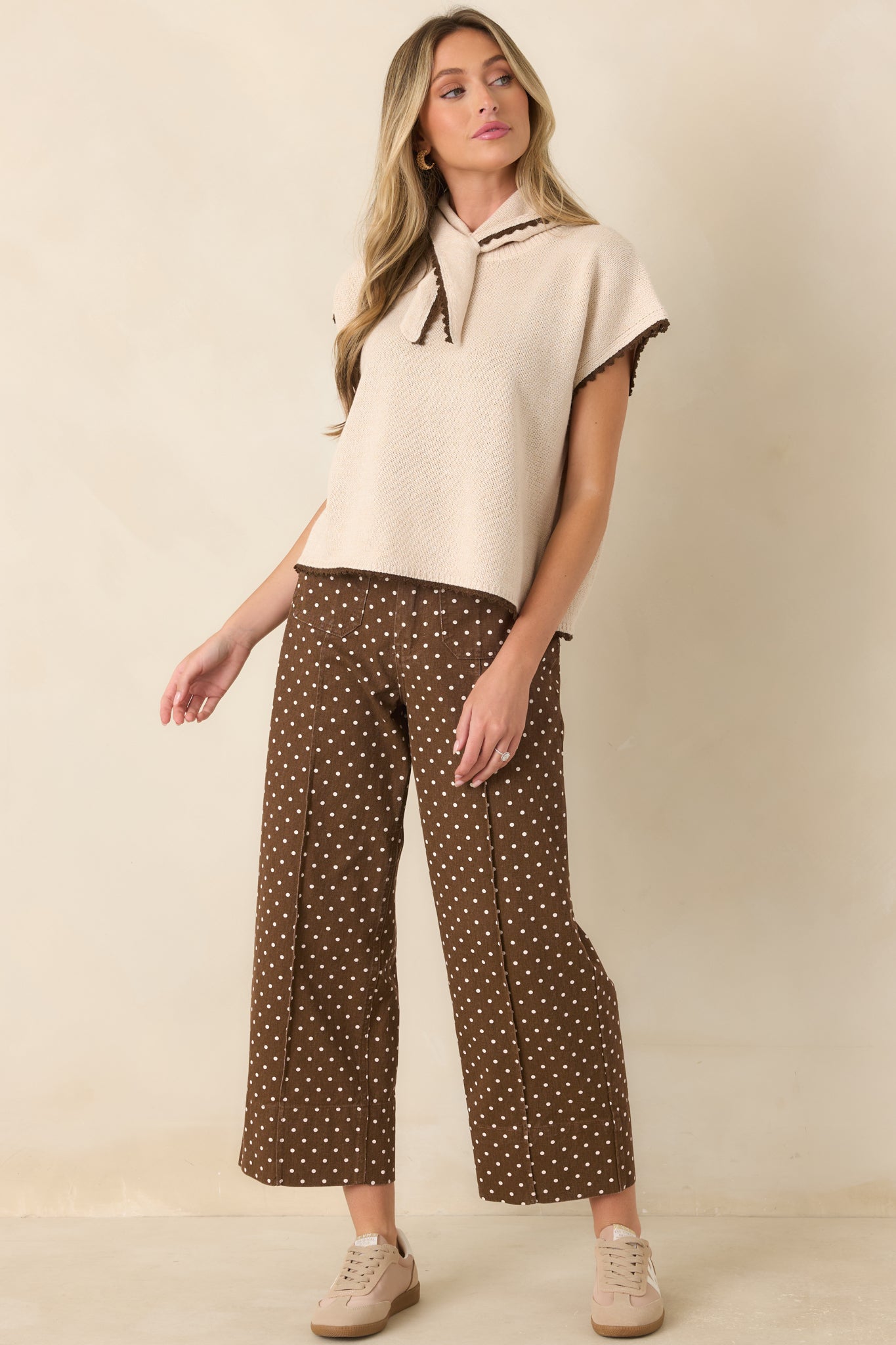 Short-sleeve ecru top showcasing a soft knit construction, scarf tie neckline, chocolate trim, and an easy boxy fit.
