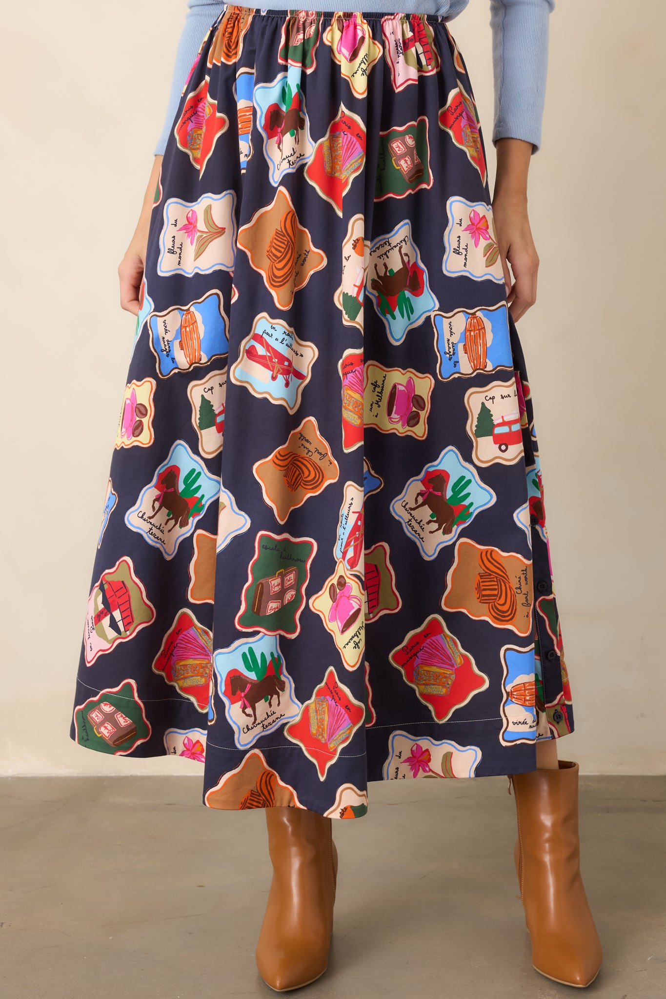 Close view of the skirt's elastic waistband and vibrant illustrated motif pattern against the deep blue cotton and lyocell fabric.