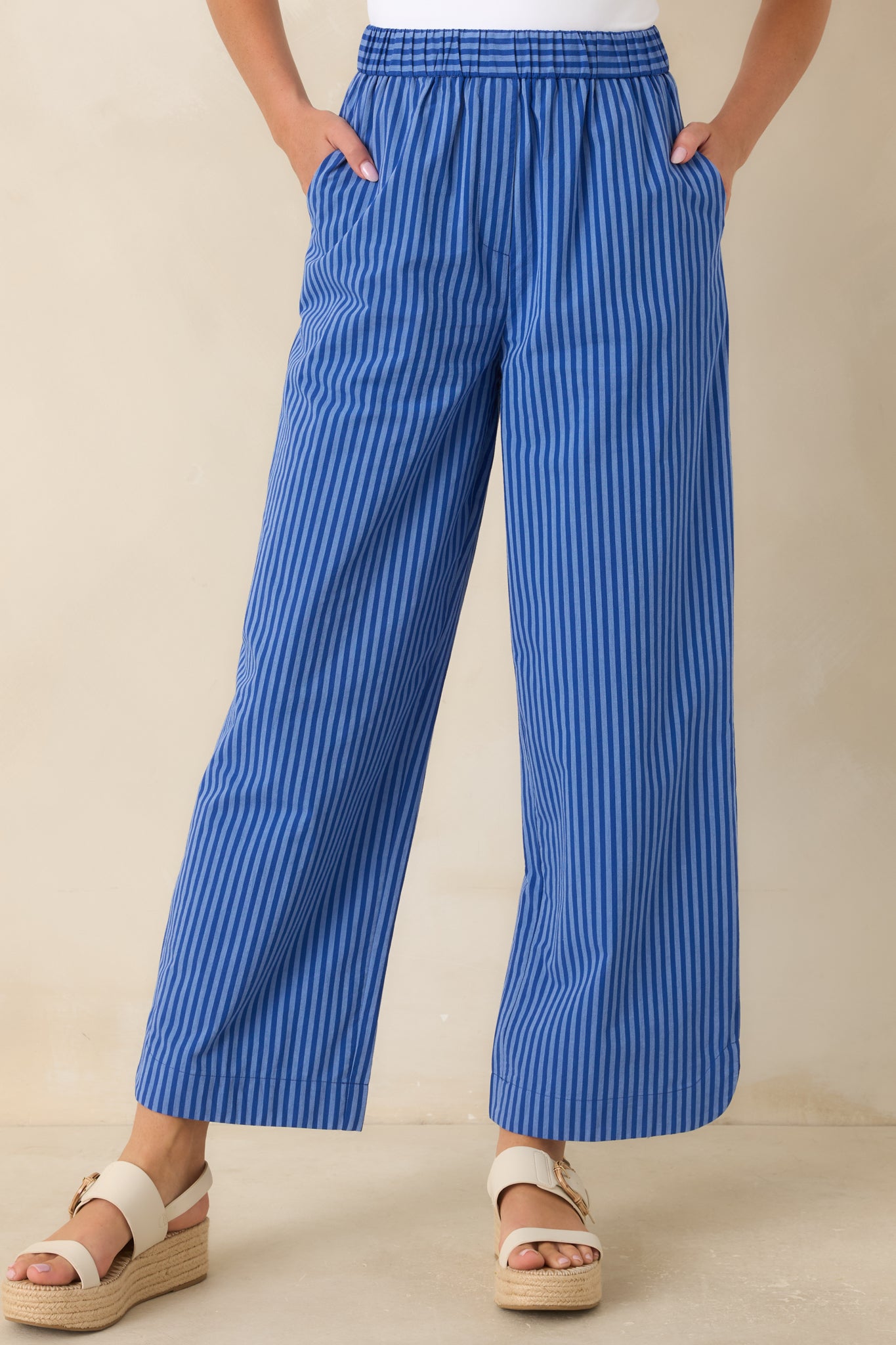Electric blue striped pants highlighting the flowing fabric, full-length design, and side pocket detailing.
