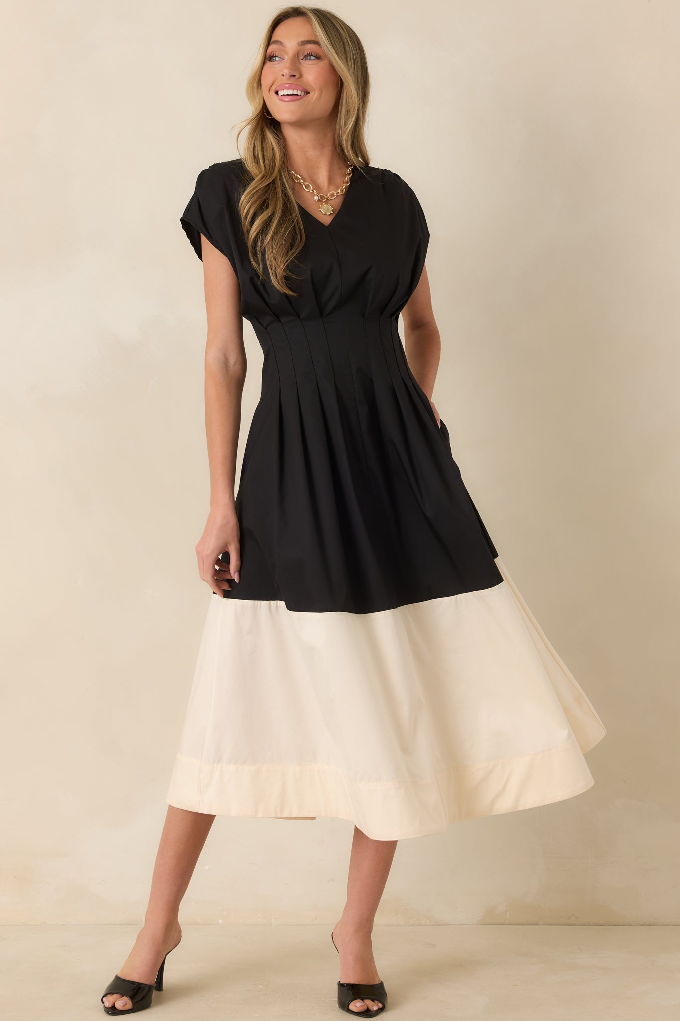 Elegant black and ivory midi dress designed with a pleated bodice, cap-style sleeves, and a polished cotton blend finish.