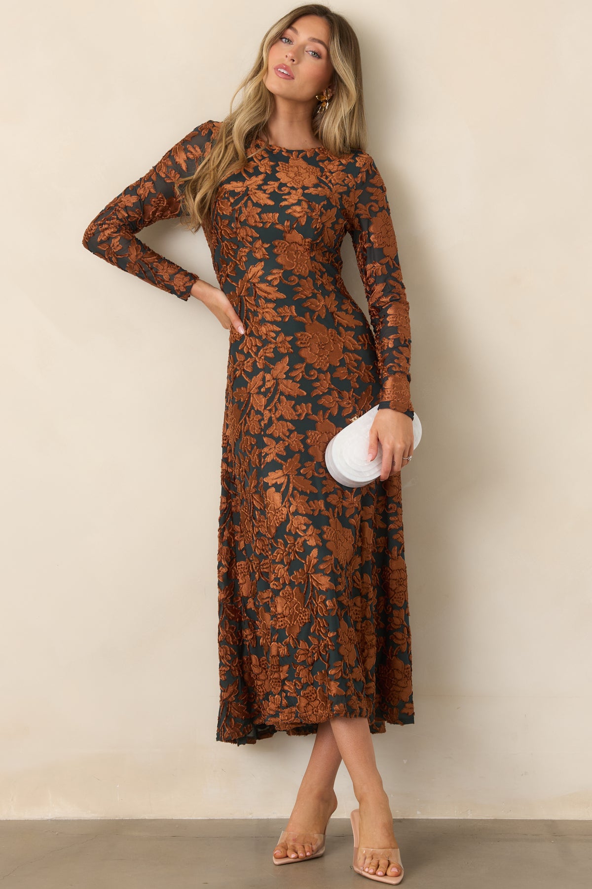 Elegant deep green midi dress with copper floral texture, a fitted bodice, long sleeves, and a softly draped skirt.
