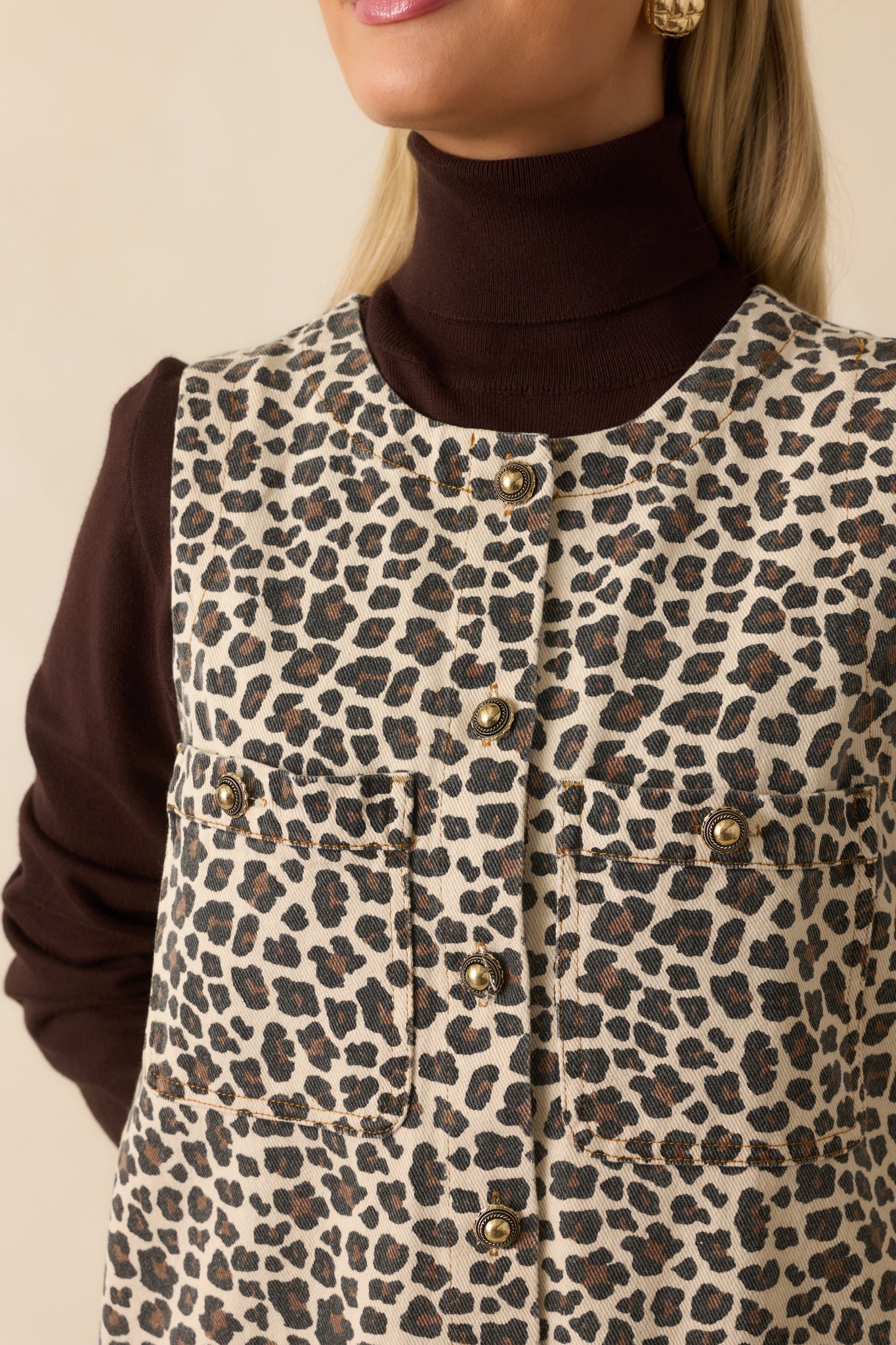 Embossed gold button detail against the leopard print denim fabric.