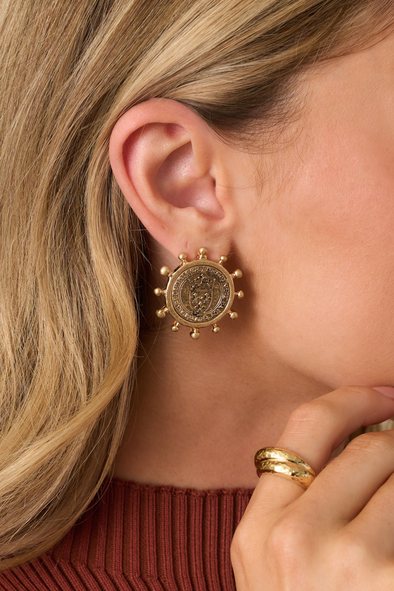 Embossed medallion earrings in a brushed gold finish, accented with evenly spaced prong details.