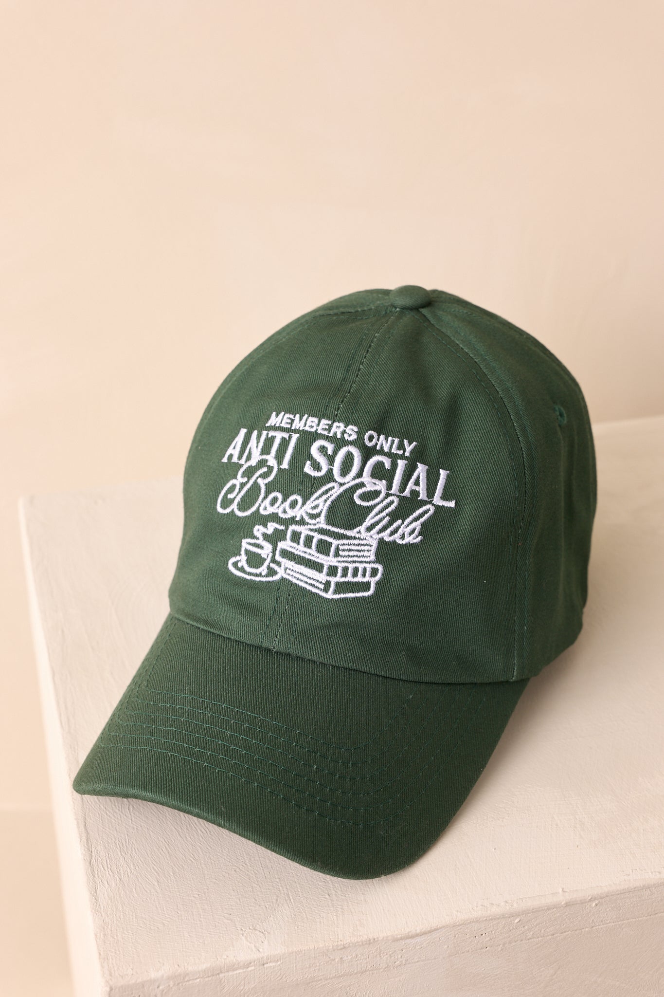 A close-up detail of the embroidered graphic showing the text, books, and coffee cup stitching.