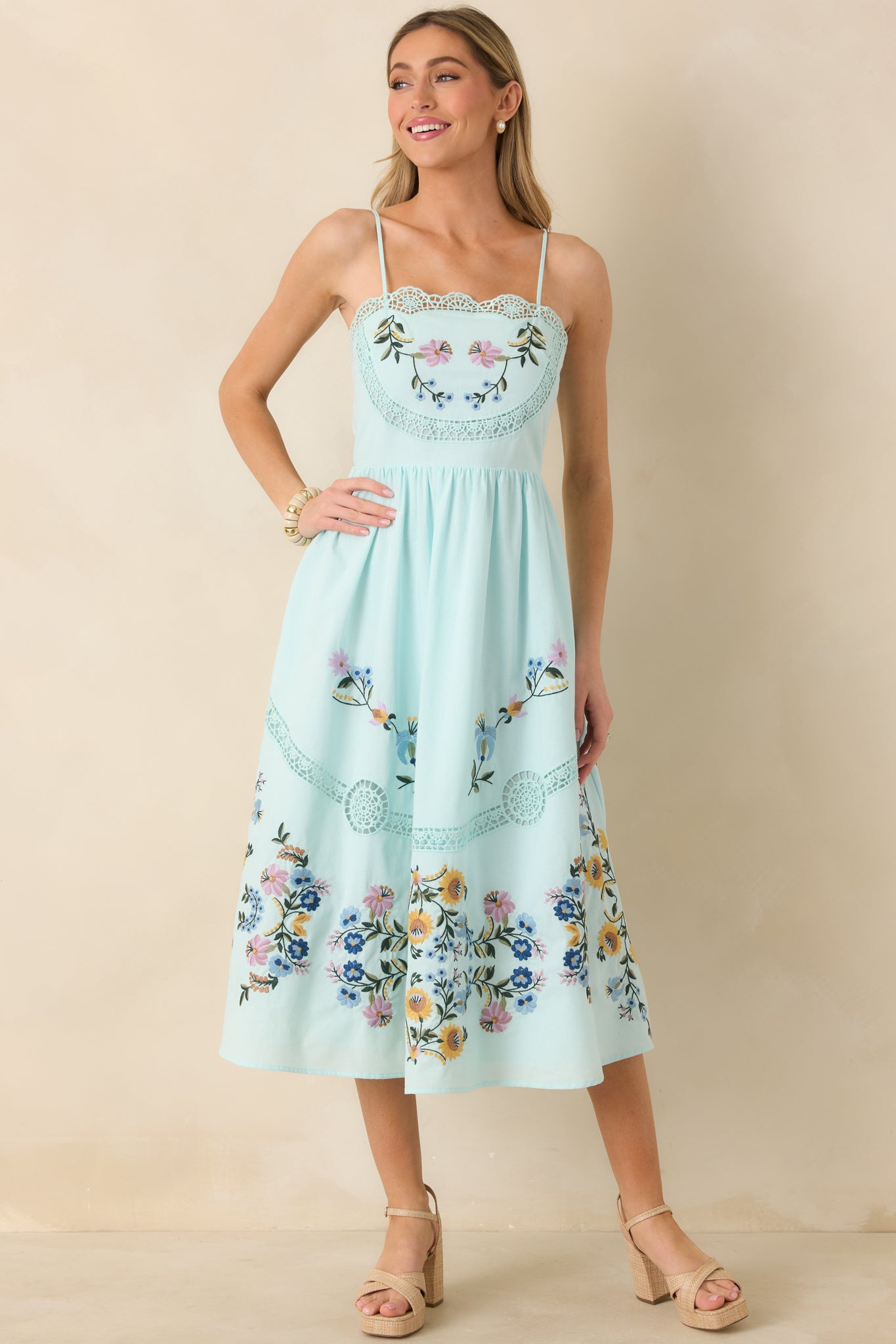Embroidered light blue dress featuring delicate lace cutouts, functional side pockets, and a flowing silhouette.
