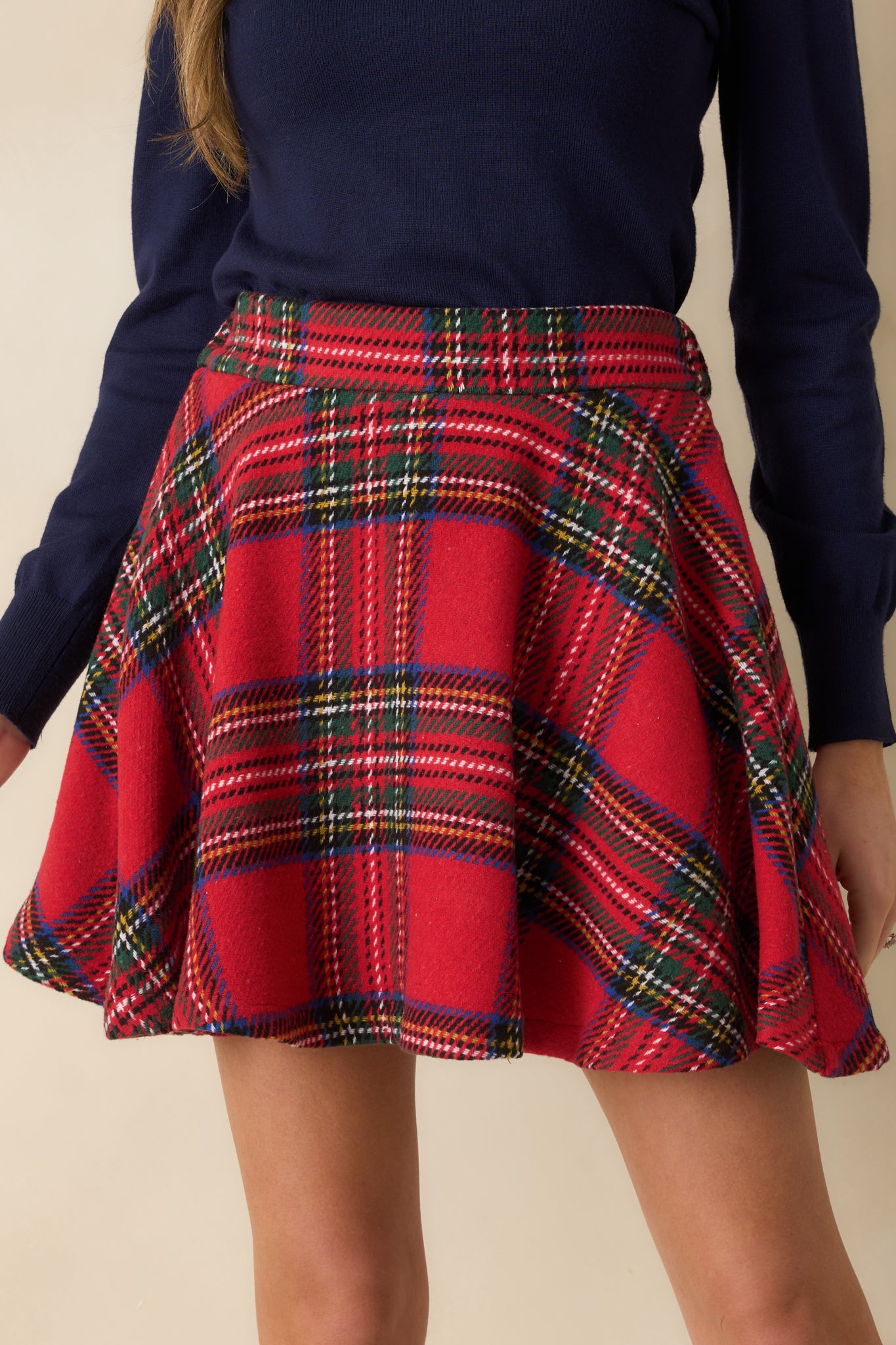 Extreme close-up of plaid mini skirt showing woven texture, structured waistband, and multicolor pattern.