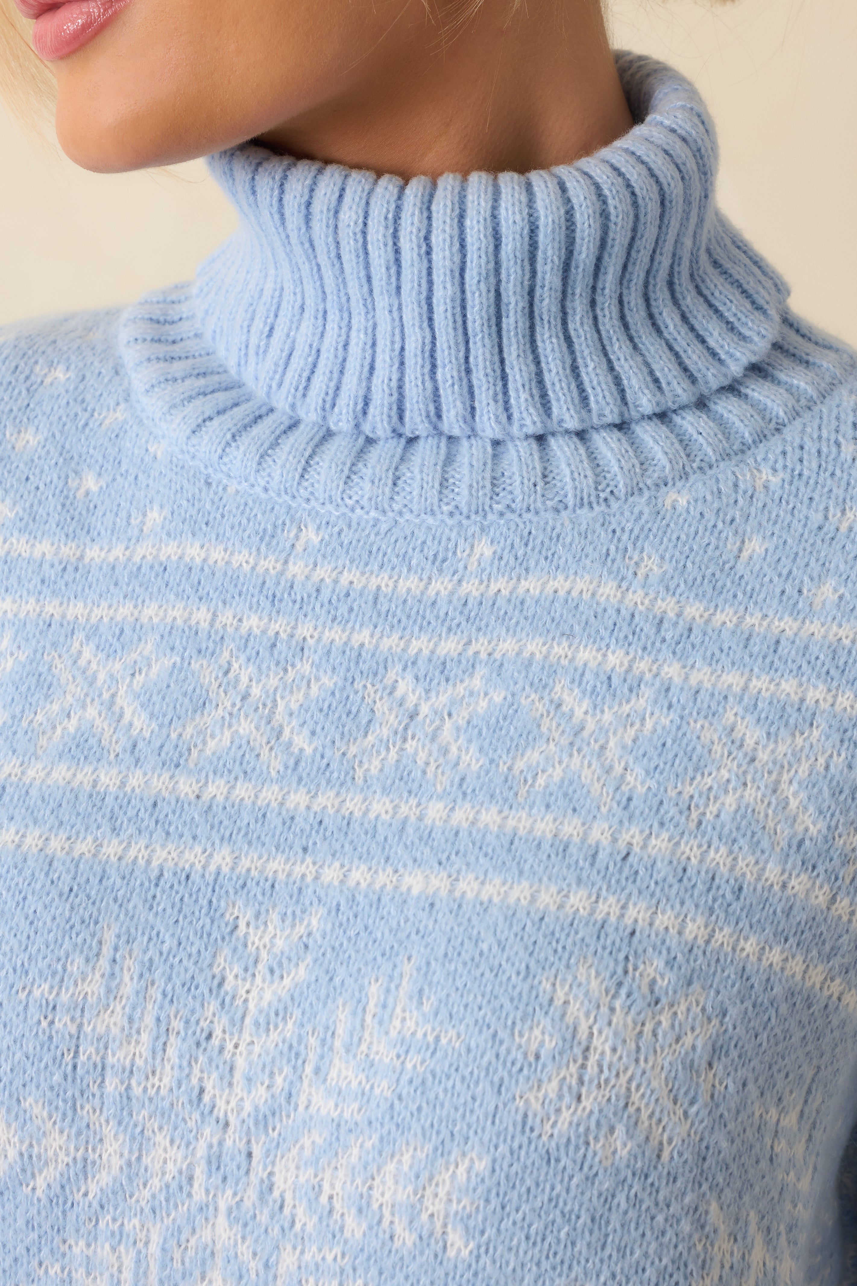 Close-up of the fair-isle and snowflake knit pattern, emphasizing the cozy texture and light blue hue.