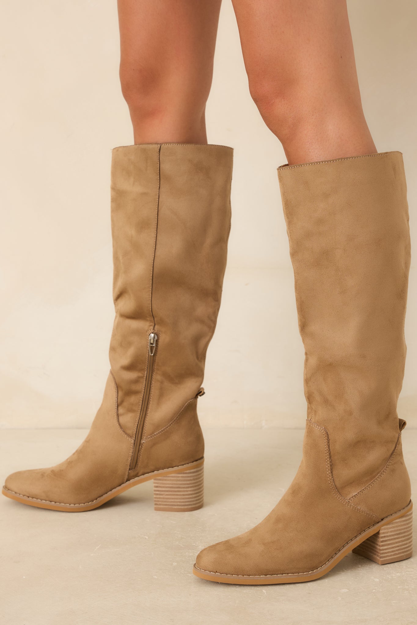 Faux suede knee-high boots in a warm tan hue with an inner side zipper closure and sleek silhouette.