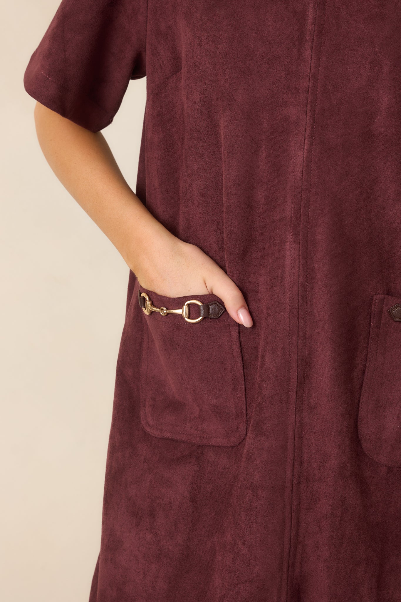 Close-up of the faux suede mini dress highlighting the front patch pocket and polished gold-tone horsebit accent.
