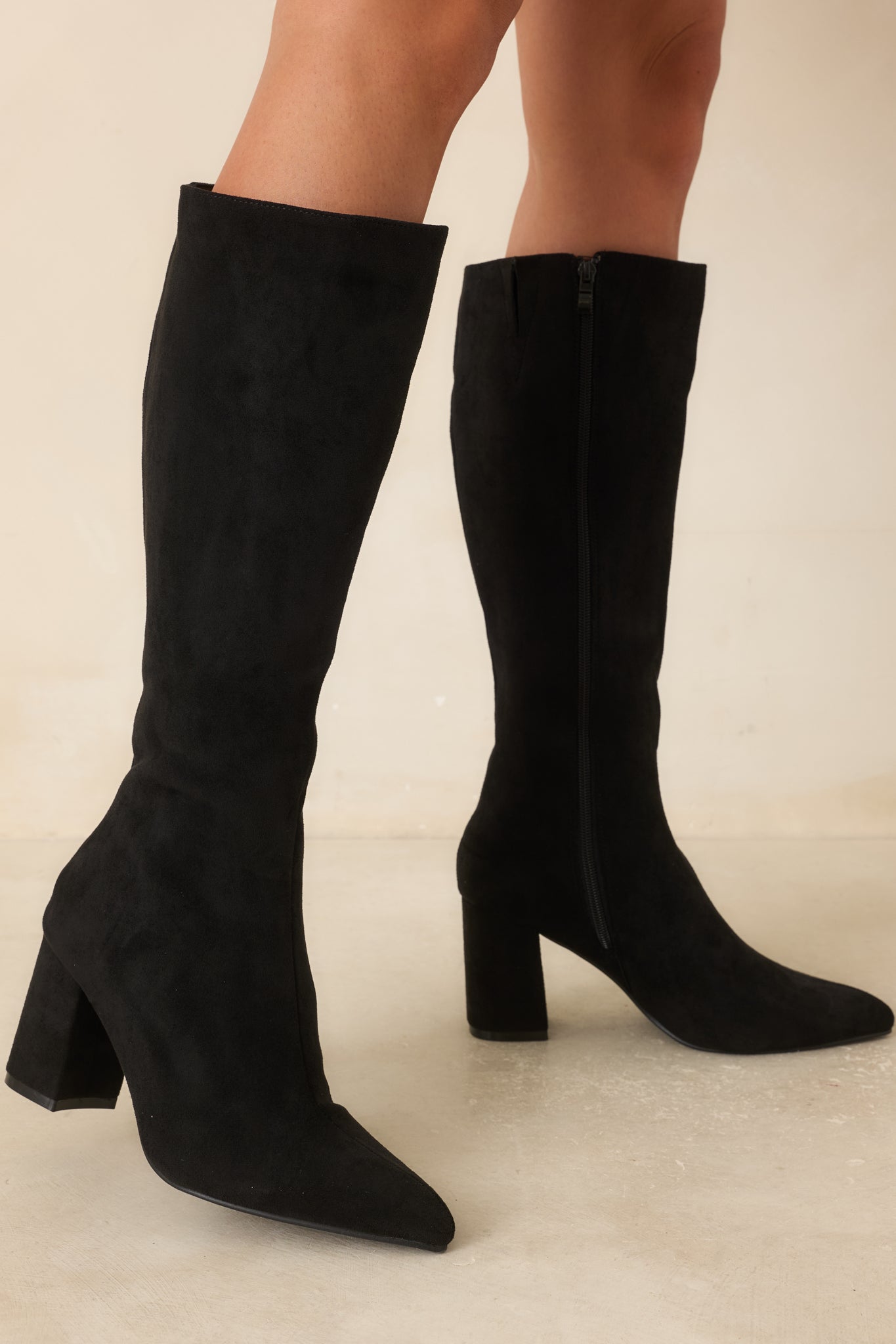 Close view of the knee-high boots highlighting the smooth faux suede texture, narrow shaft design, and refined pointed toe shape.