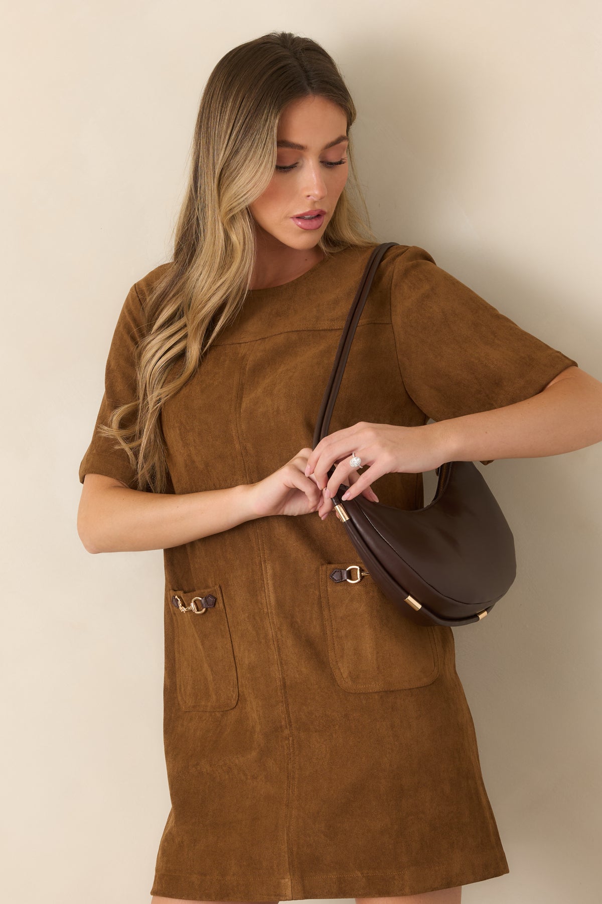 Faux suede mini dress highlighting the round neckline, short sleeves, and gold-tone horsebit accents across the front.