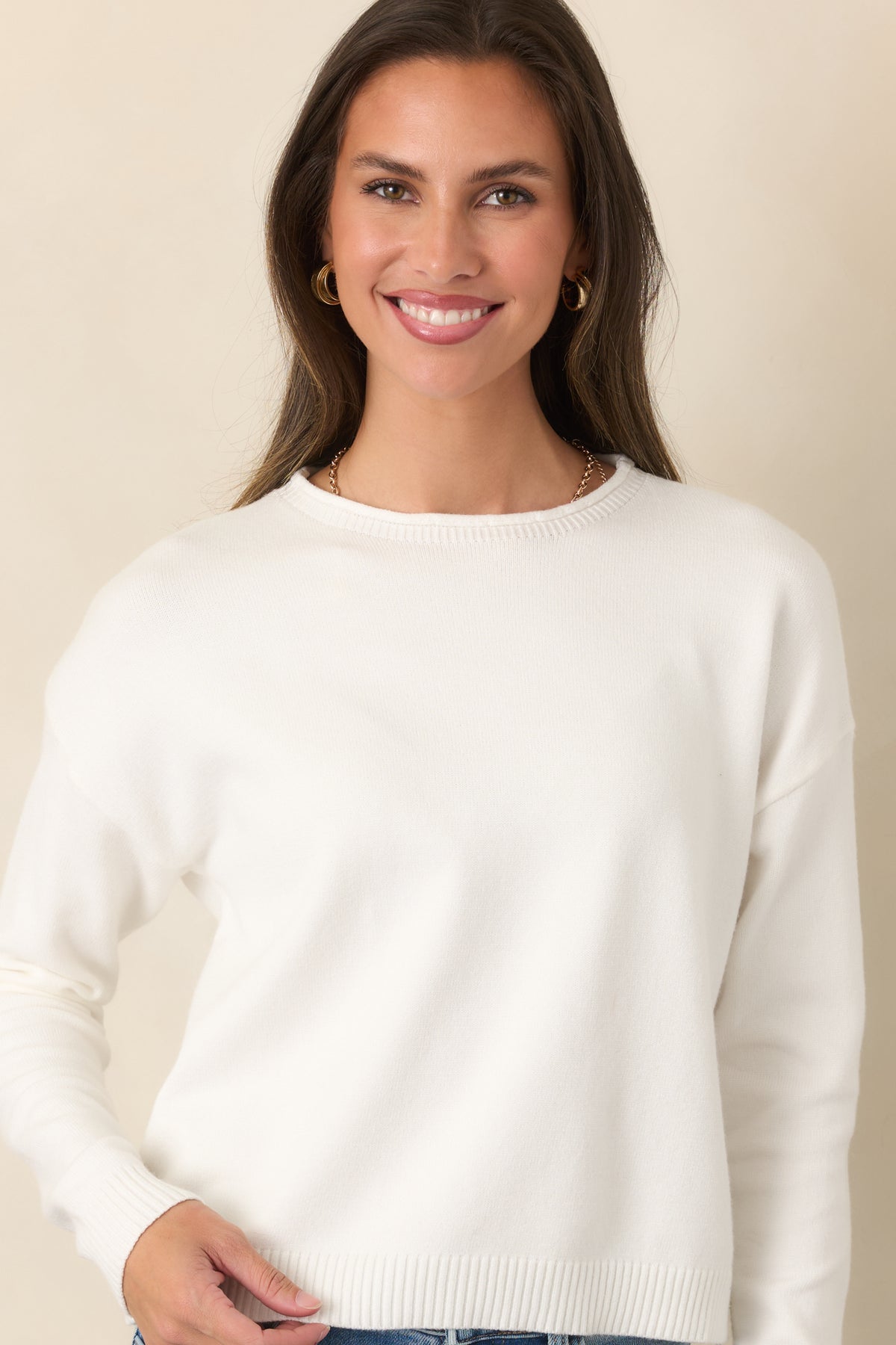 Fine ivory knit frames the crew neckline with neatly finished ribbed edging.