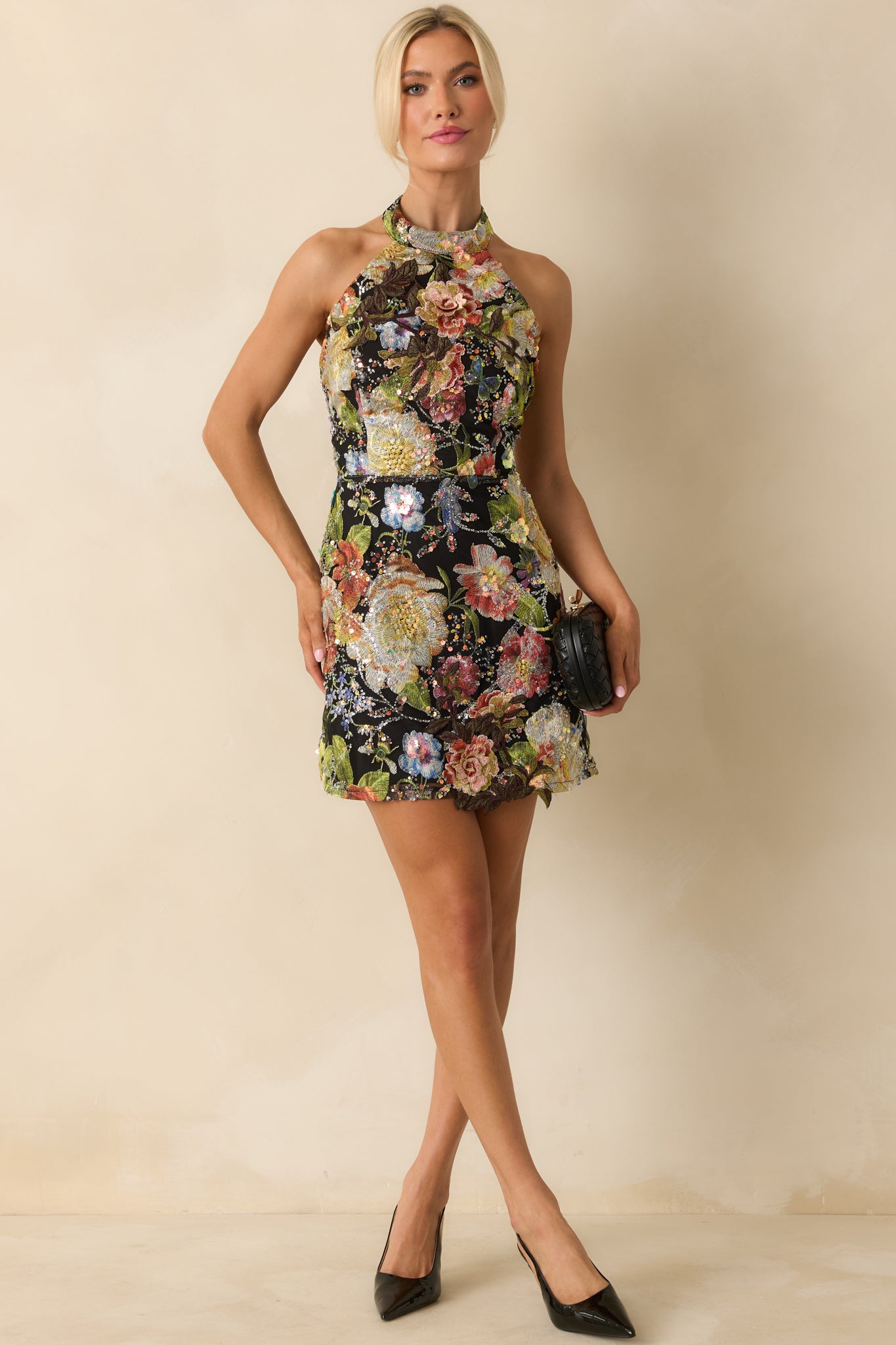 Fitted black mini dress featuring sparkling floral sequin pattern and sleeveless halter cut.