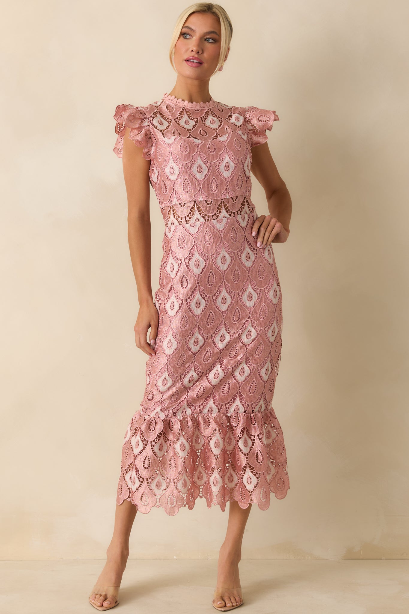 The fitted bodice and flowing maxi skirt emphasize the intricate lace pattern and delicate flounce.