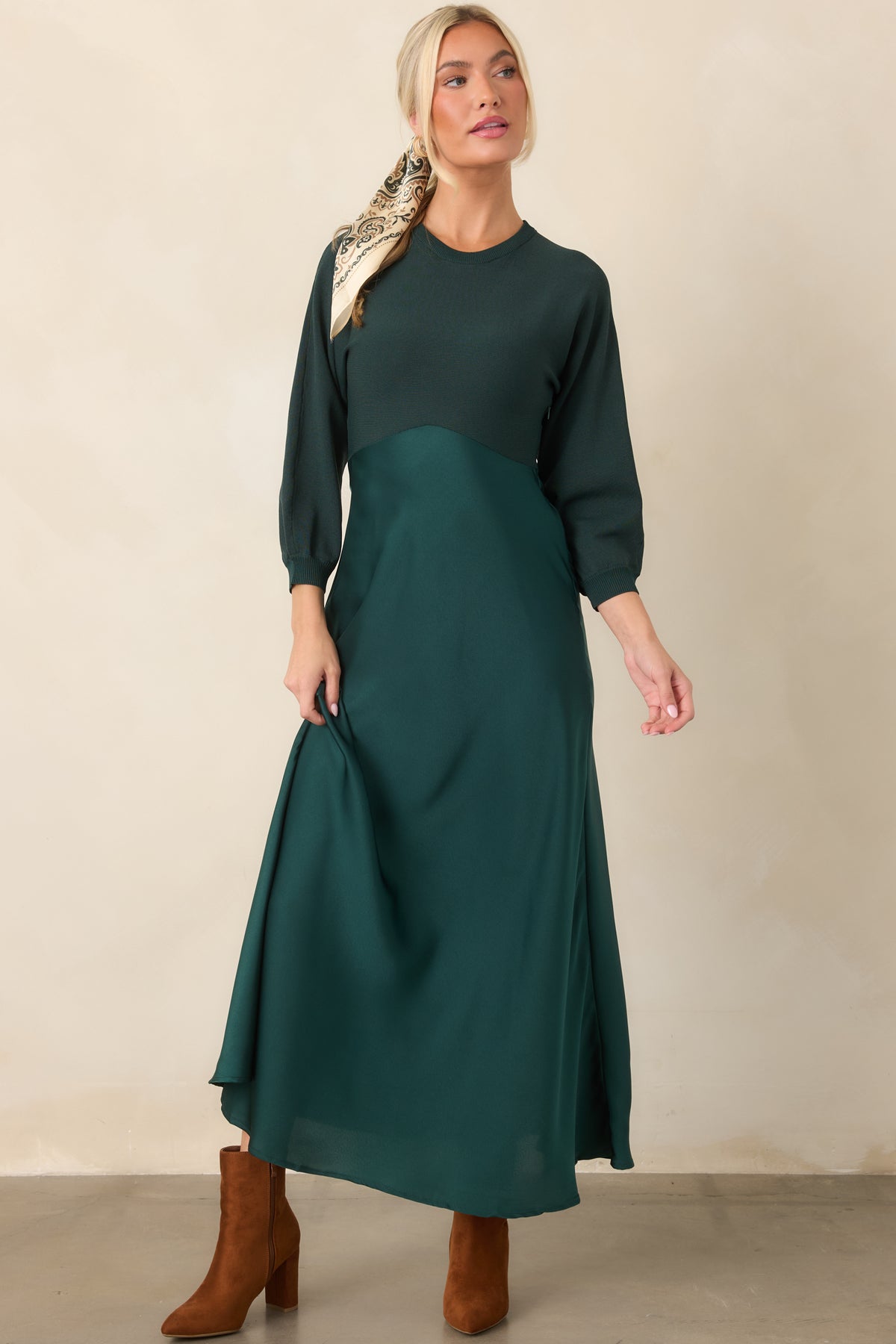 Fitted emerald knit bodice meets a satin midi skirt, creating an elegant A-line dress with three-quarter sleeves.