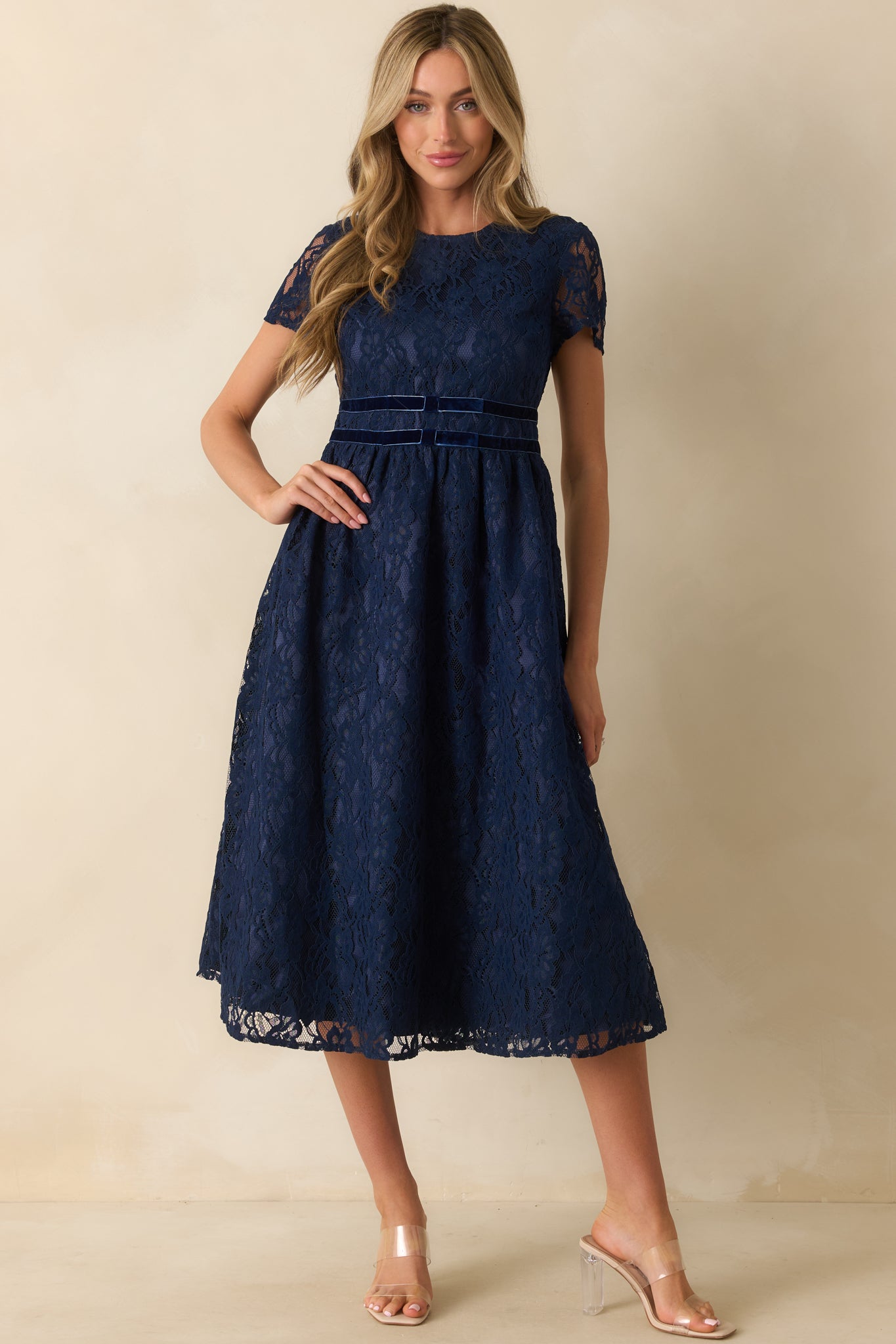 Fitted navy lace dress accented with velvet waist trim and delicate floral lace overlay.