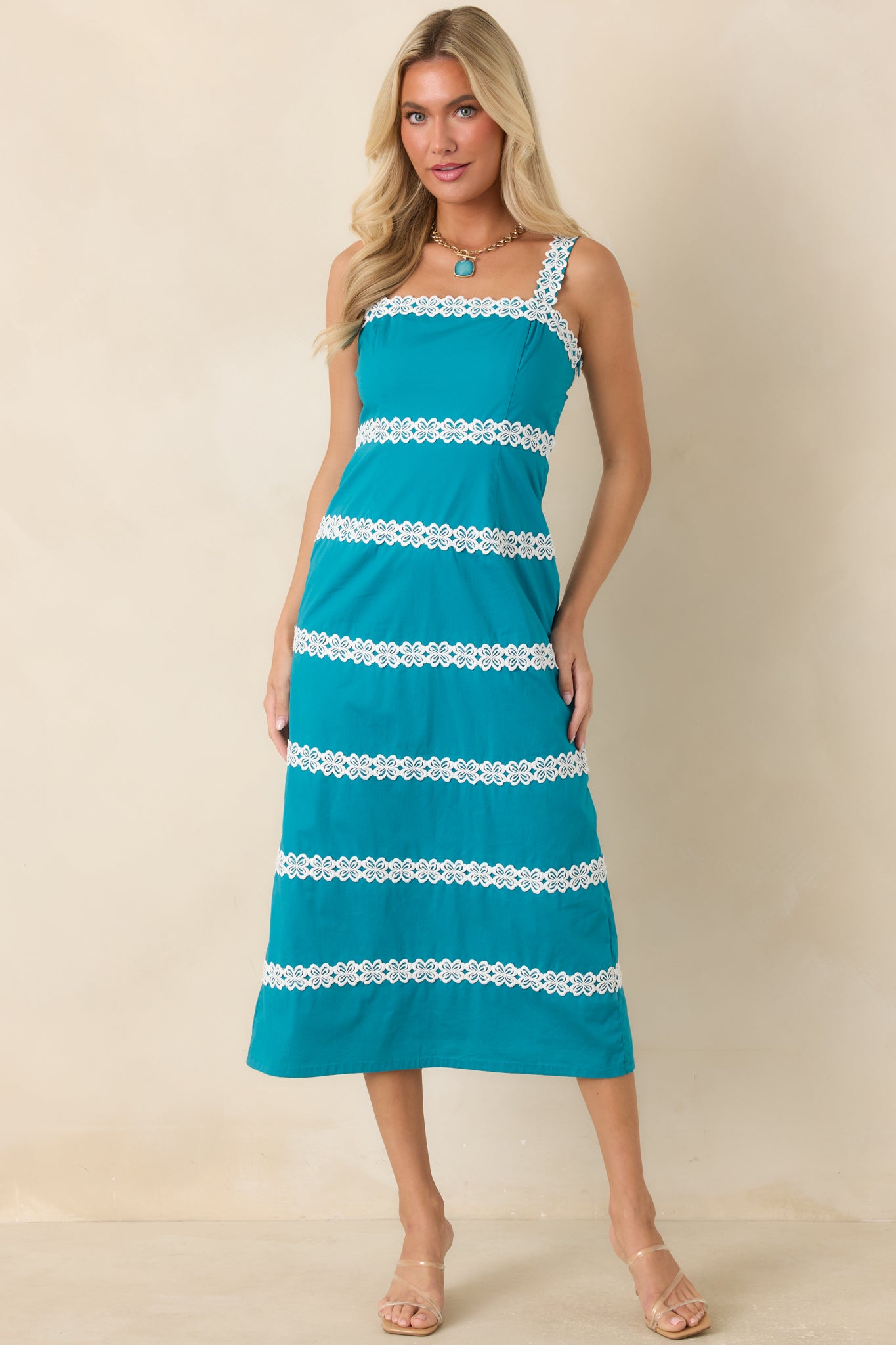 Fitted teal dress showcasing rows of ivory floral lace and a polished square neckline.