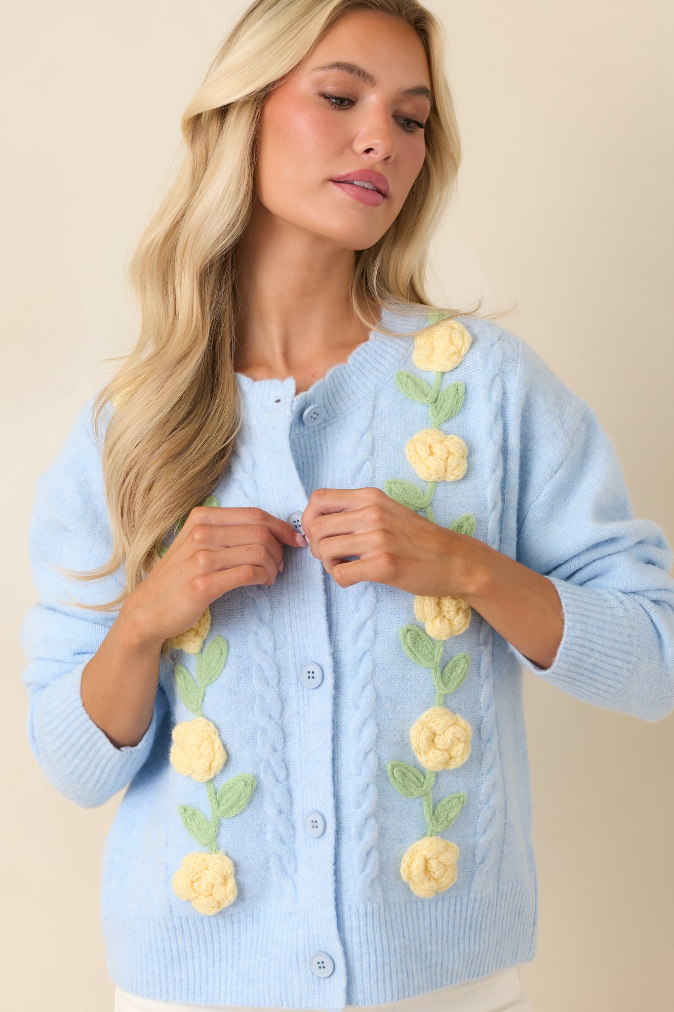 Close view of the raised floral appliqués, ribbed neckline, and soft knit texture on the cardigan.