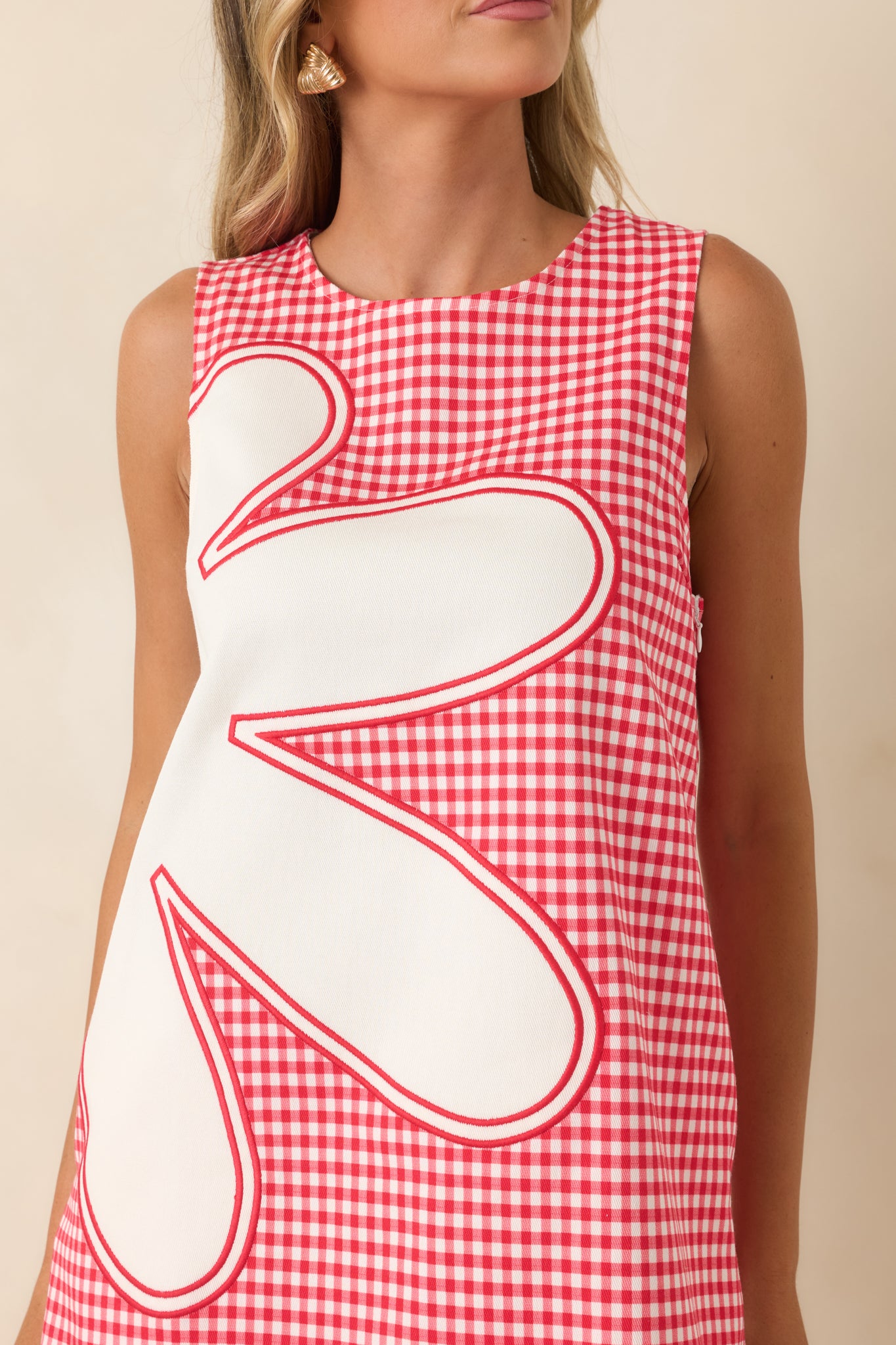 Close-up of the oversized floral appliqué showcasing its dimensional texture against the red gingham fabric.