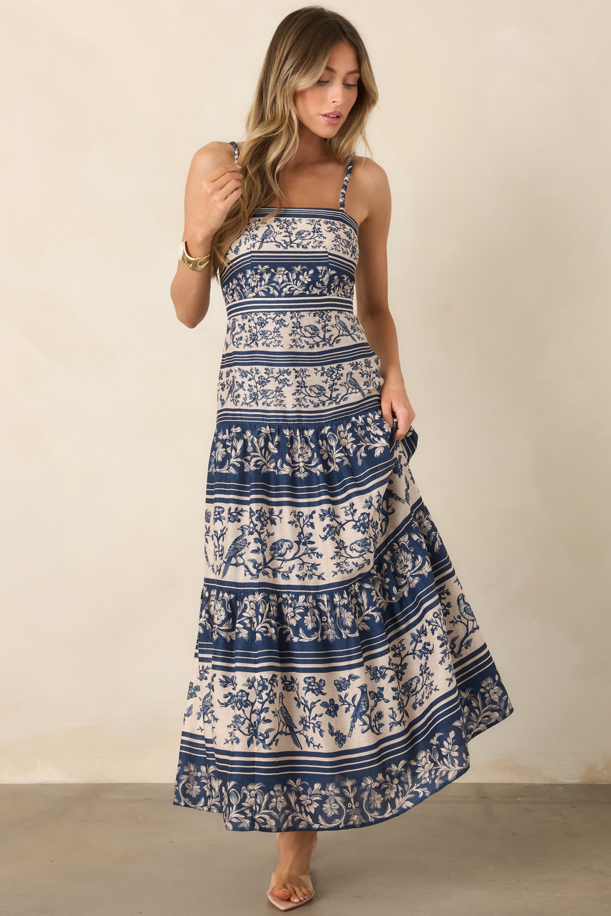 Floral borders and winding branches accent the bird-print design, while the tiered skirt adds movement to the silhouette.