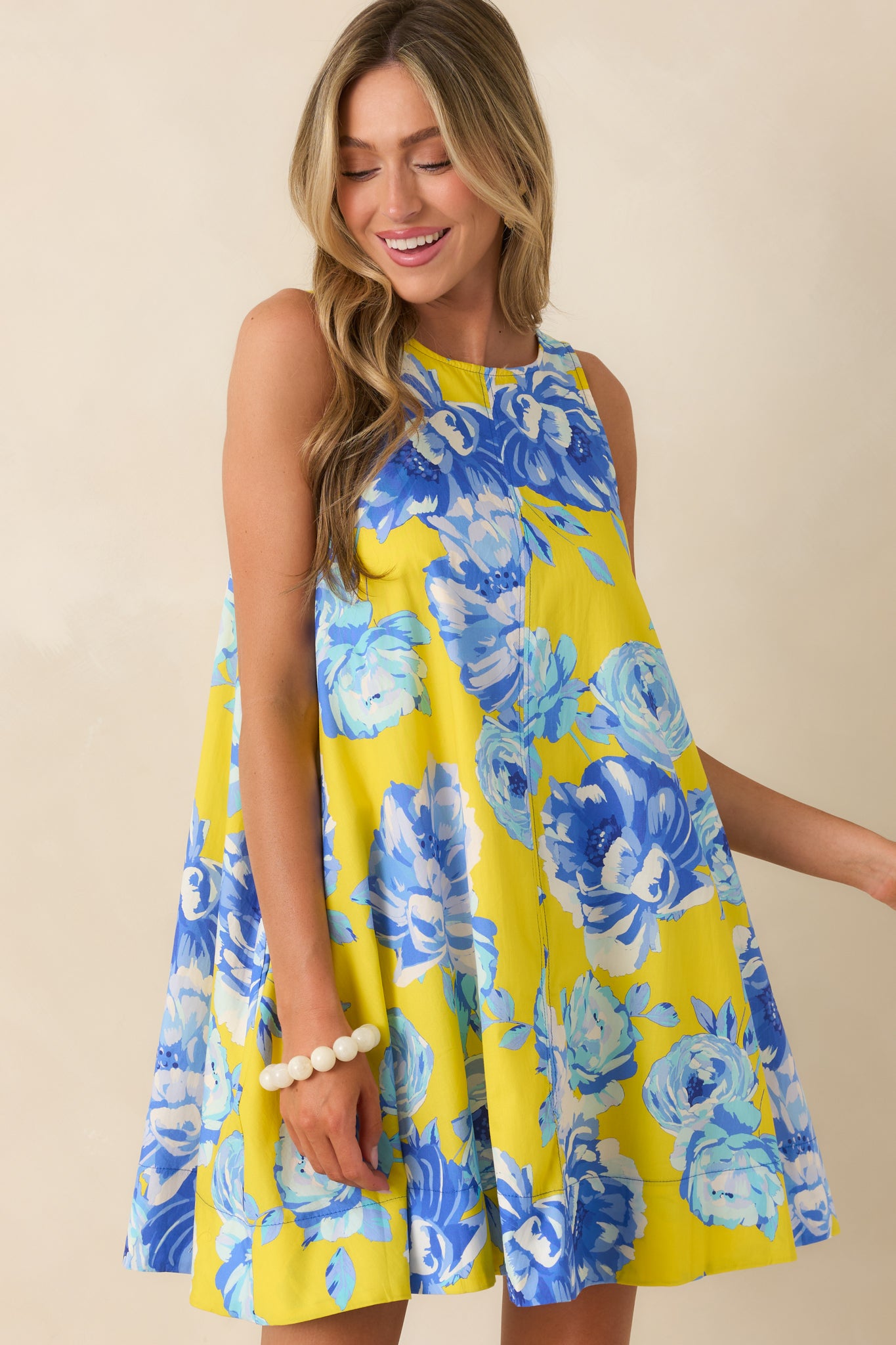 Close view of the round neckline and sleeveless arm openings on the floral cotton mini dress.