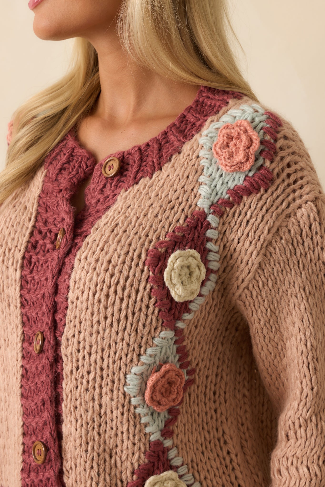 Close-up of the multicolor floral crochet appliqués and chunky knit fabric on the cardigan.