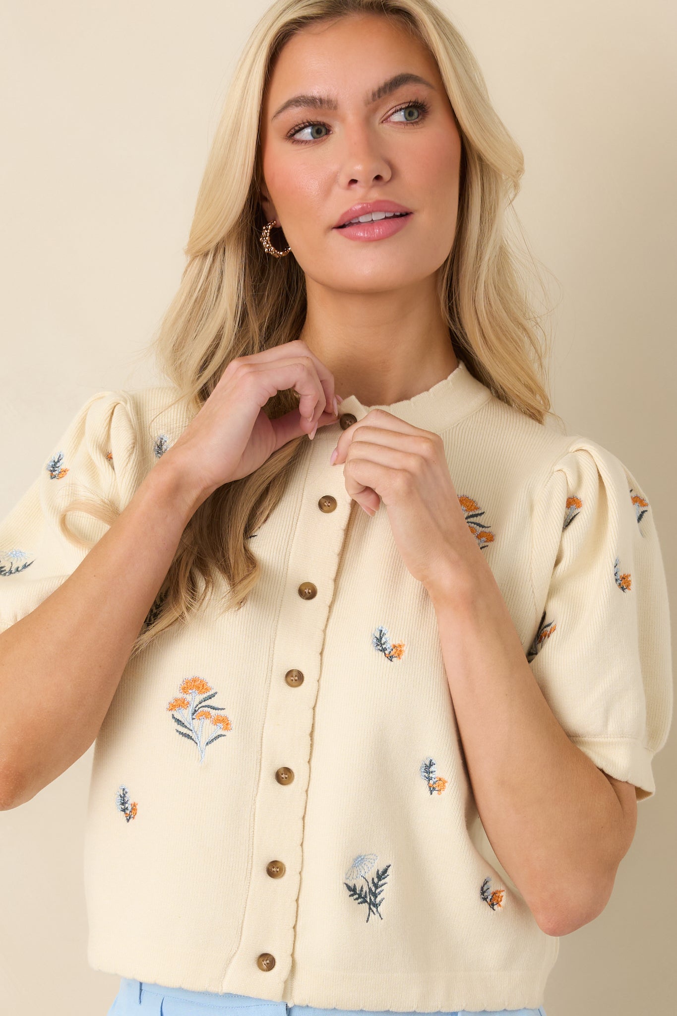Floral embroidery detail across ivory knit surface with soft, medium-weight texture.