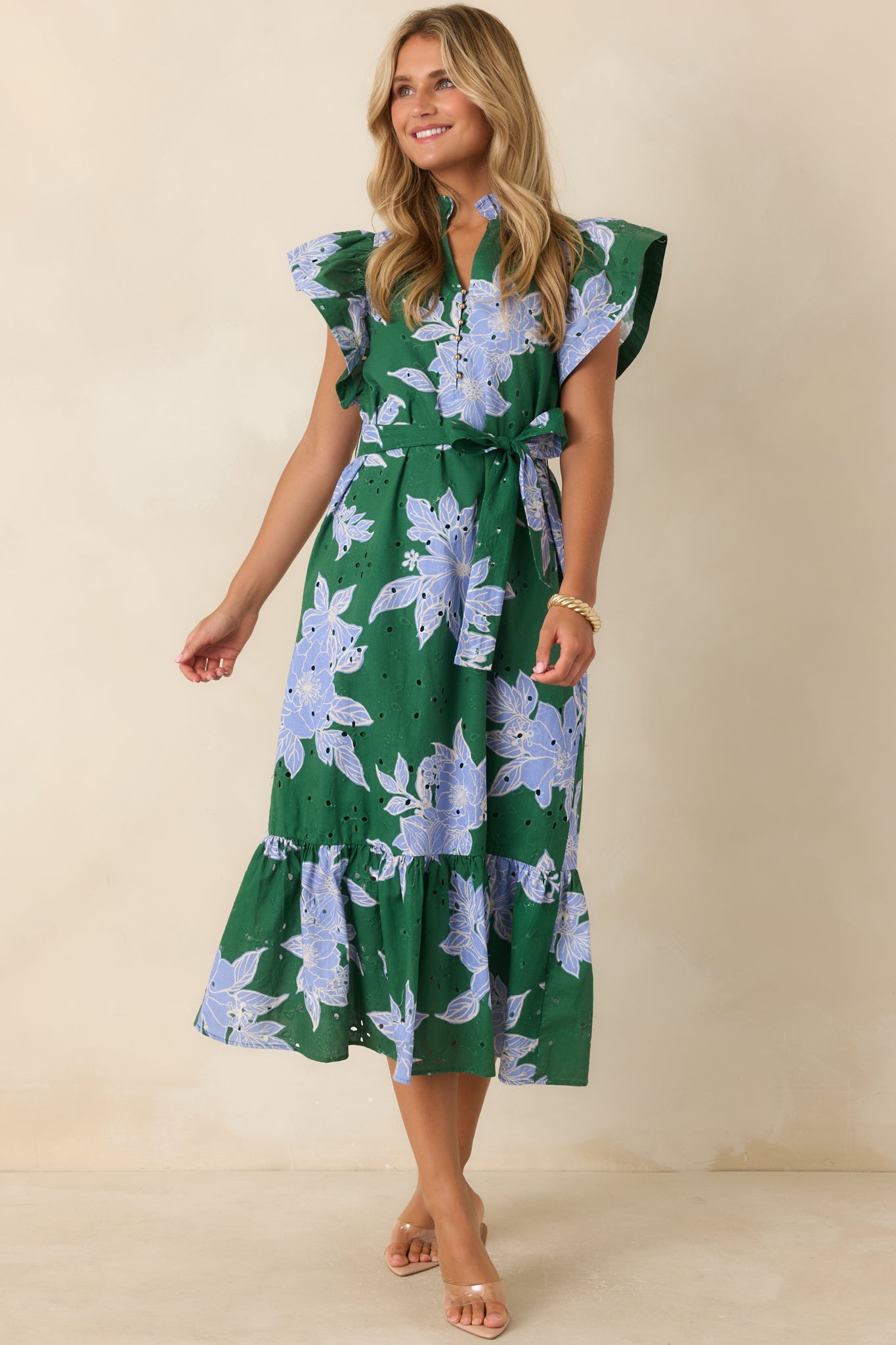 Floral eyelet midi dress featuring a ruffled neckline, flutter sleeves, self-tie belt, side pockets, and relaxed elegance.