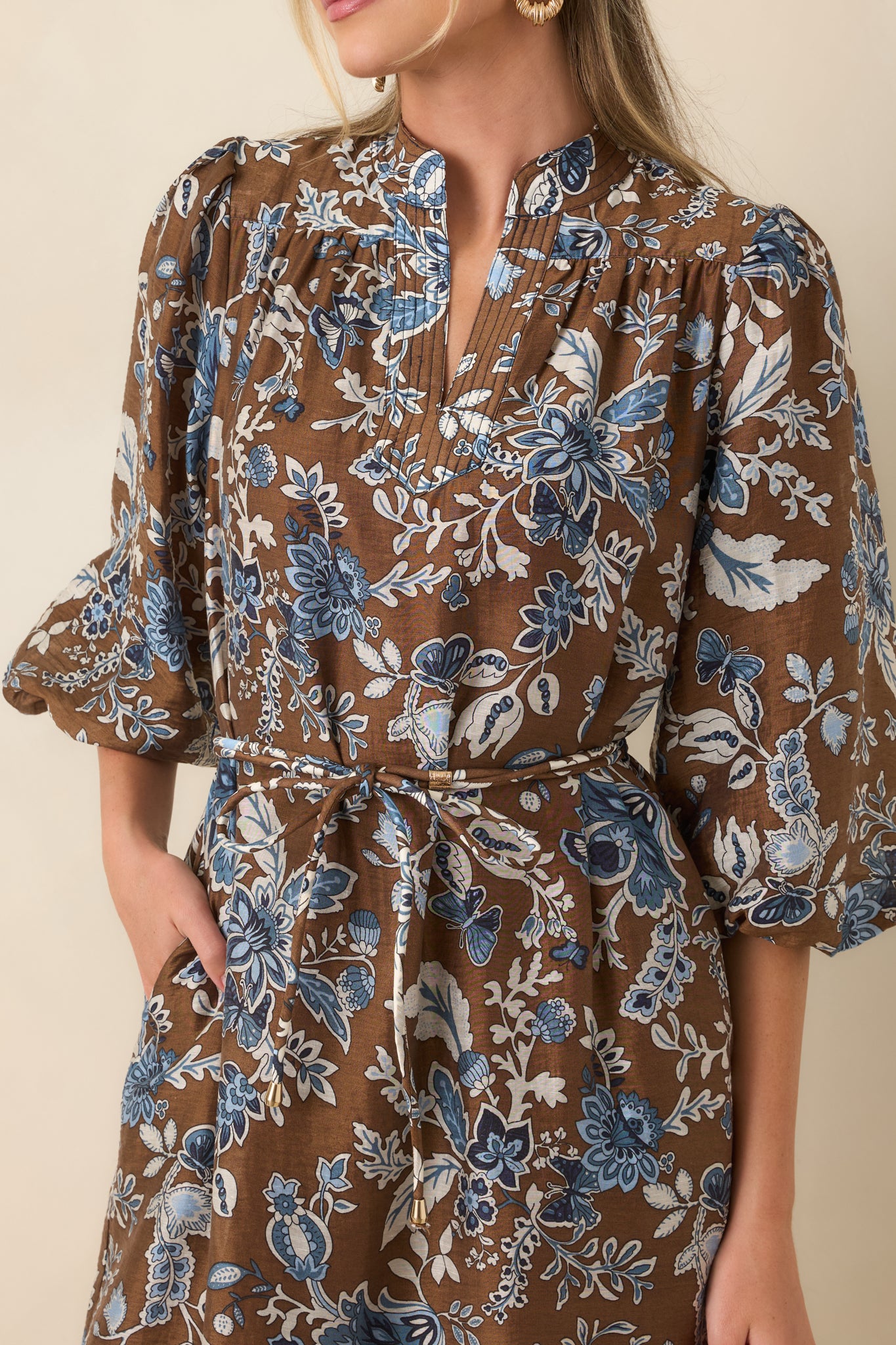 Close-up of the floral midi dress highlighting the split band collar, pintuck neckline, blue floral pattern, and soft fabric texture.
