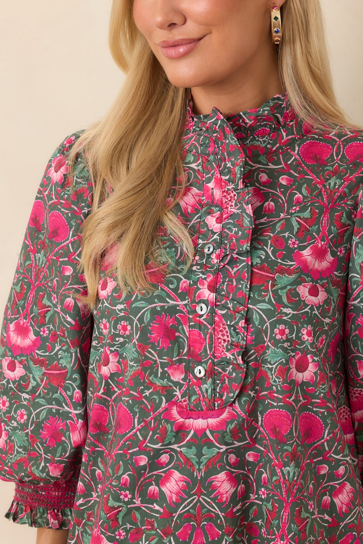 Ruffled stand collar and partial button placket framed by a vibrant pink floral print.