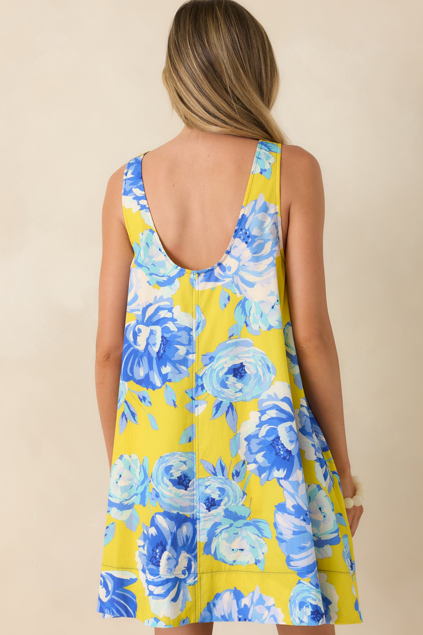 Back view of the floral mini dress featuring a sleeveless silhouette, round neckline, and relaxed swing shape in lightweight cotton.