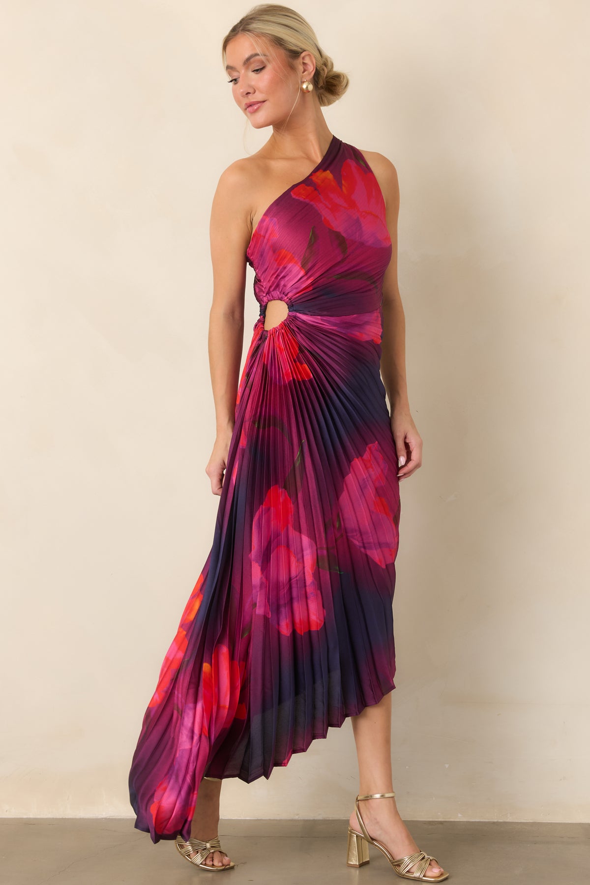 The dramatic floral print meets a sleek one-shoulder neckline, ruched waist, and gracefully uneven hemline.