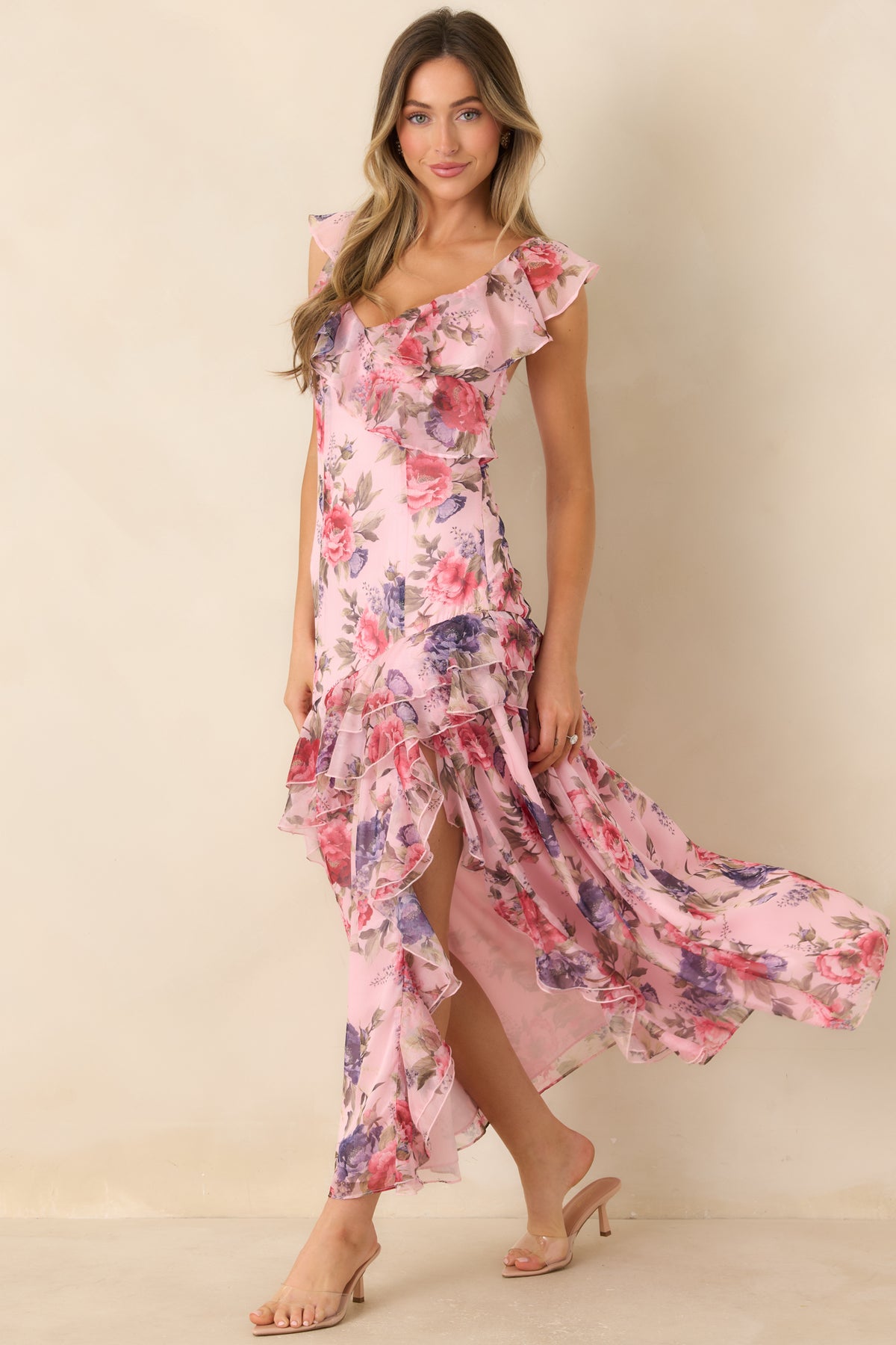 Floral maxi dress with an airy pink base, cascading shoulder ruffles, and a softly flowing silhouette.