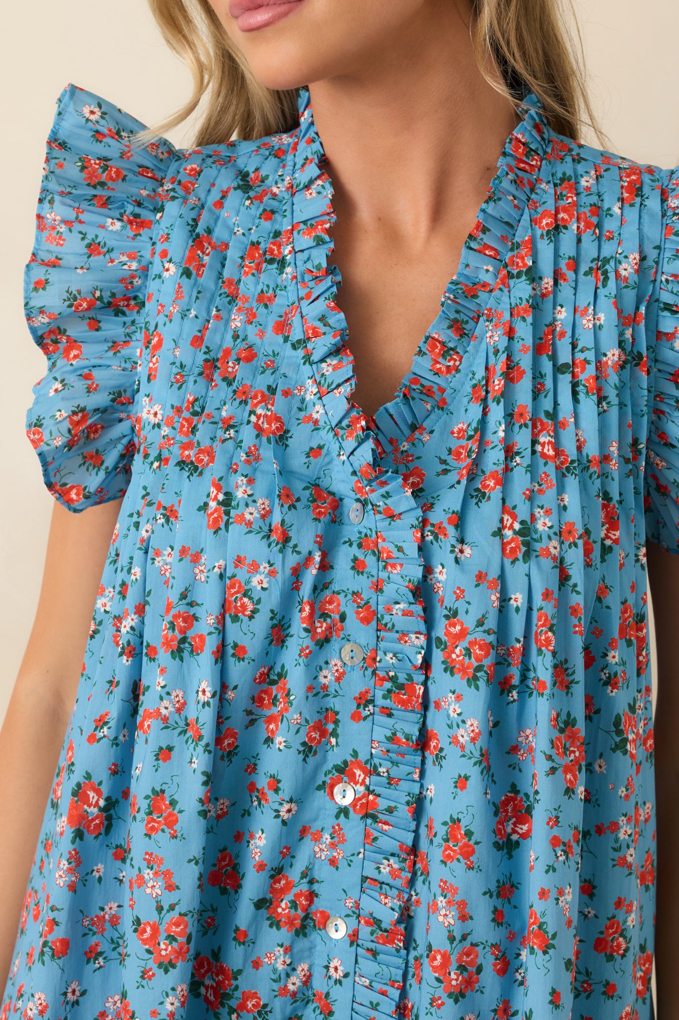 Detailed view of the floral print, ruffled V-neckline, pleated yoke, and front button detailing.