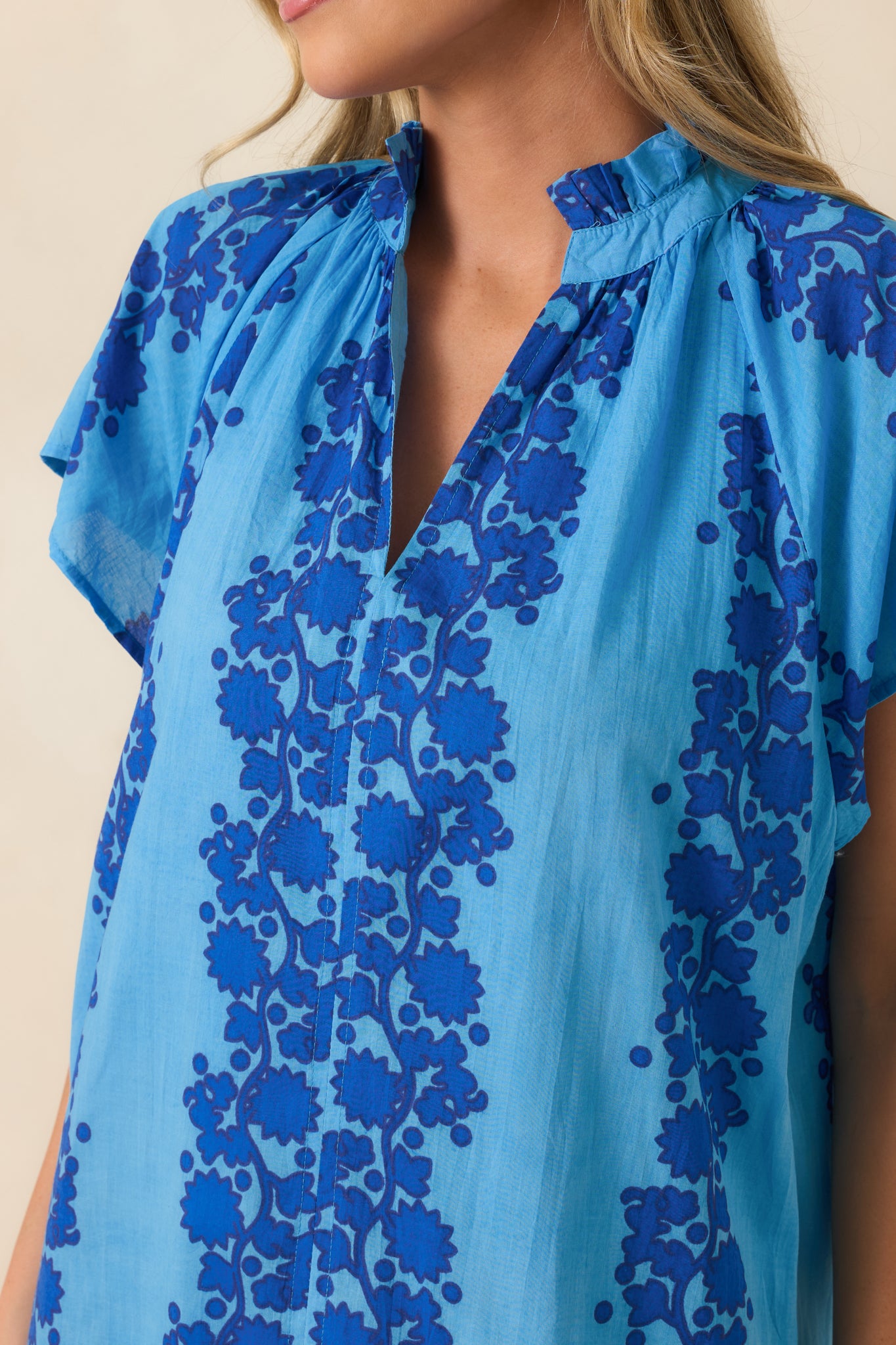 Close-up of the floral print, ruffle-trimmed neckline, and lightweight cotton texture