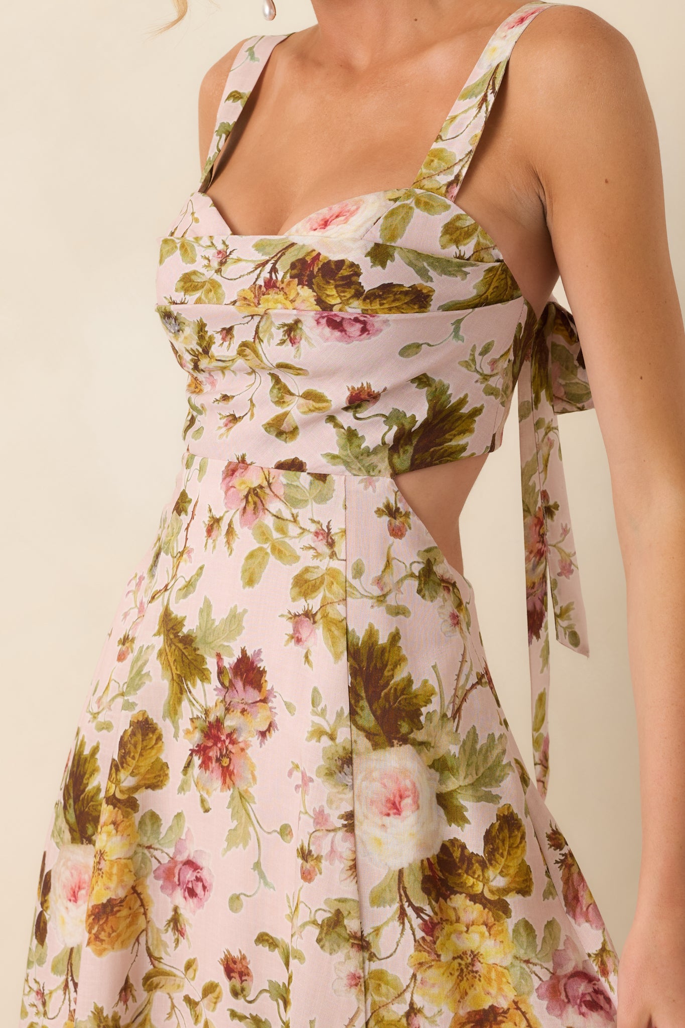 Detailed view of the floral print, sweetheart neckline, pleated bust, and adjustable self-tie straps.
