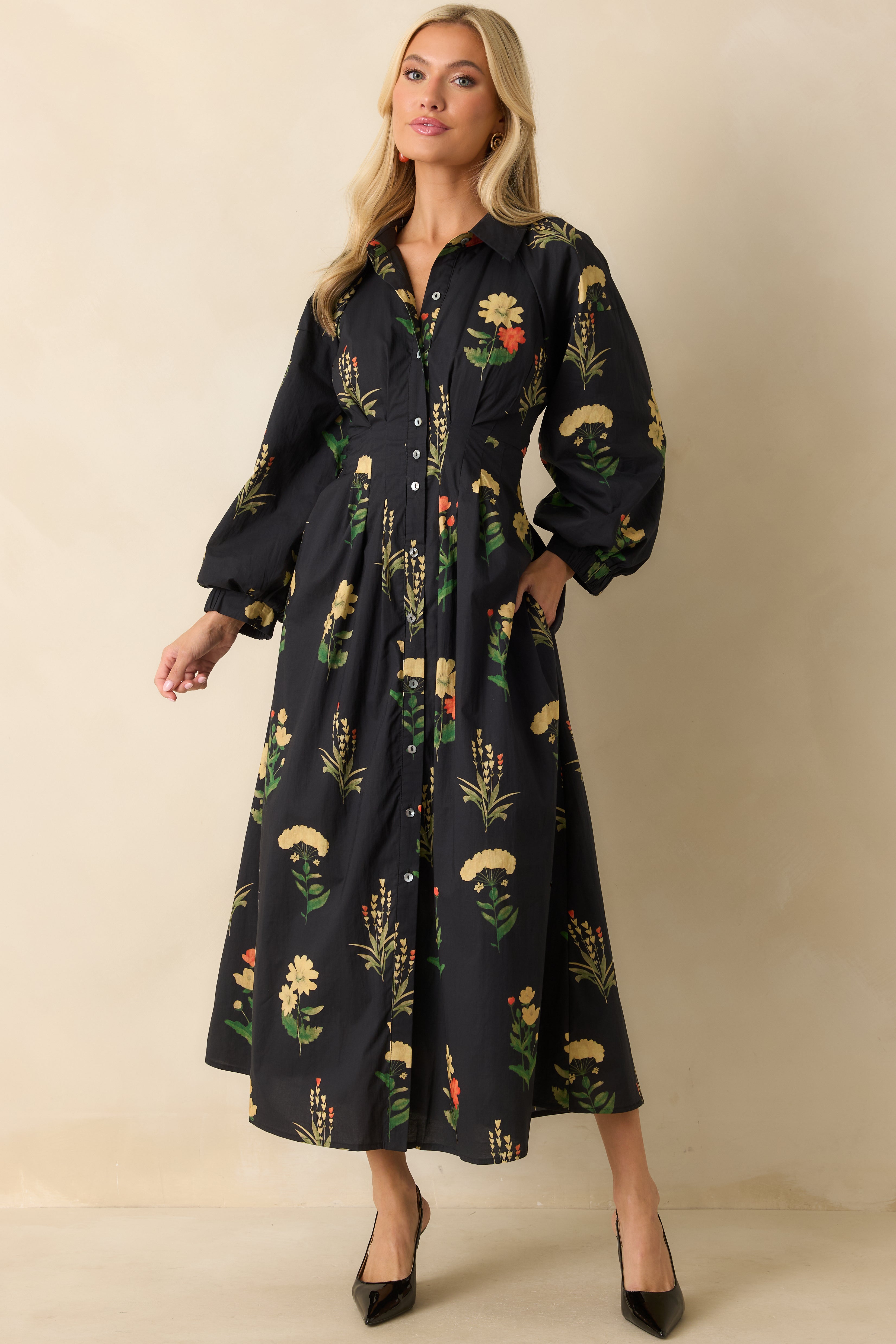 Floral print black dress featuring pleated waist, side pockets, and flowing ankle-length silhouette.