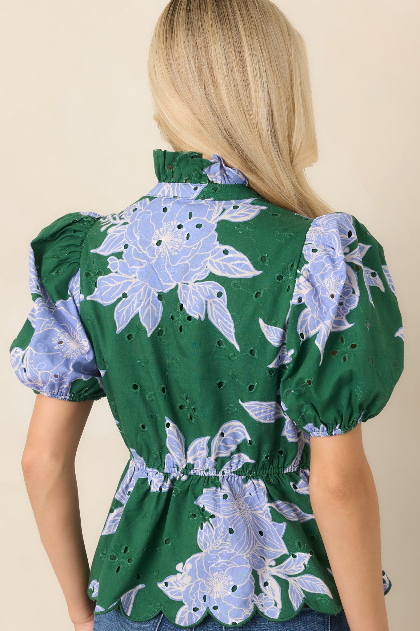 Rear view of the floral-print top showcasing its elasticized back waist, puff sleeves, and scalloped hem.