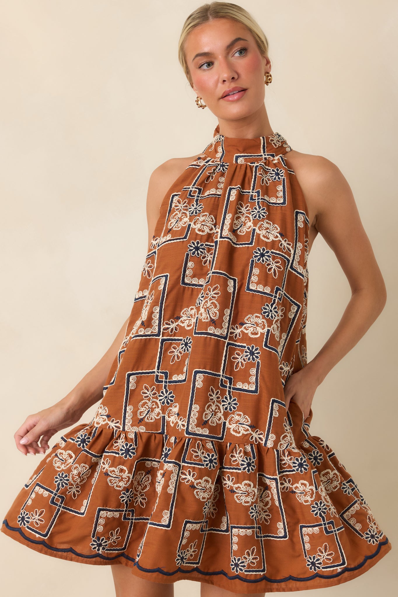 Mini dress detail featuring the flounced hem and decorative embroidered fabric texture.