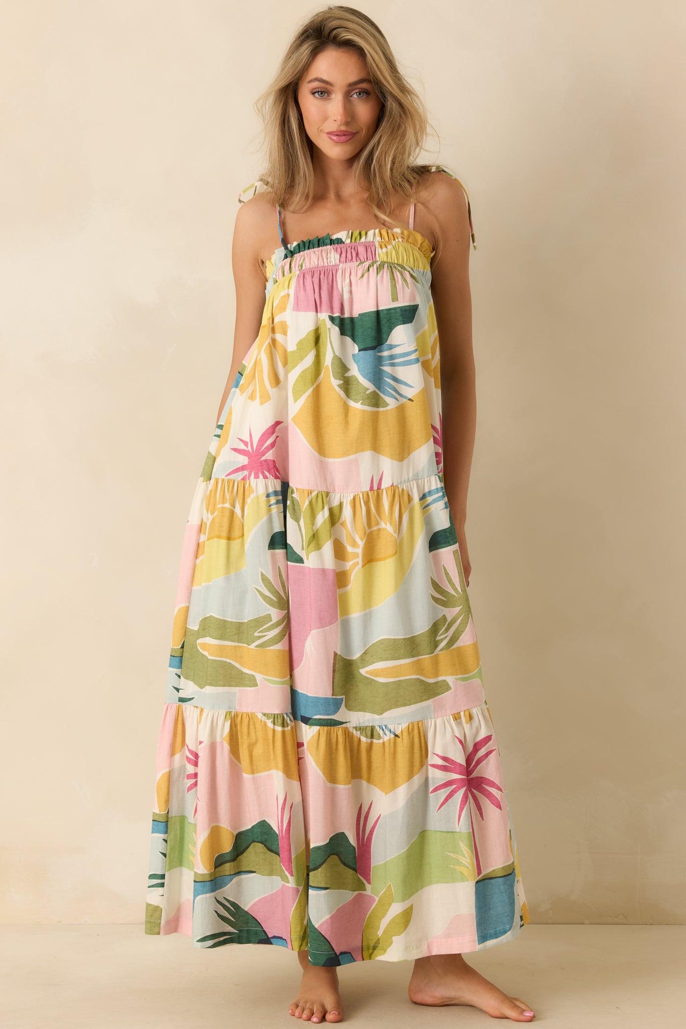 Flowing maxi dress showcasing a tropical lagoon pattern, adjustable shoulder ties, and softly draped tiered panels throughout the skirt.