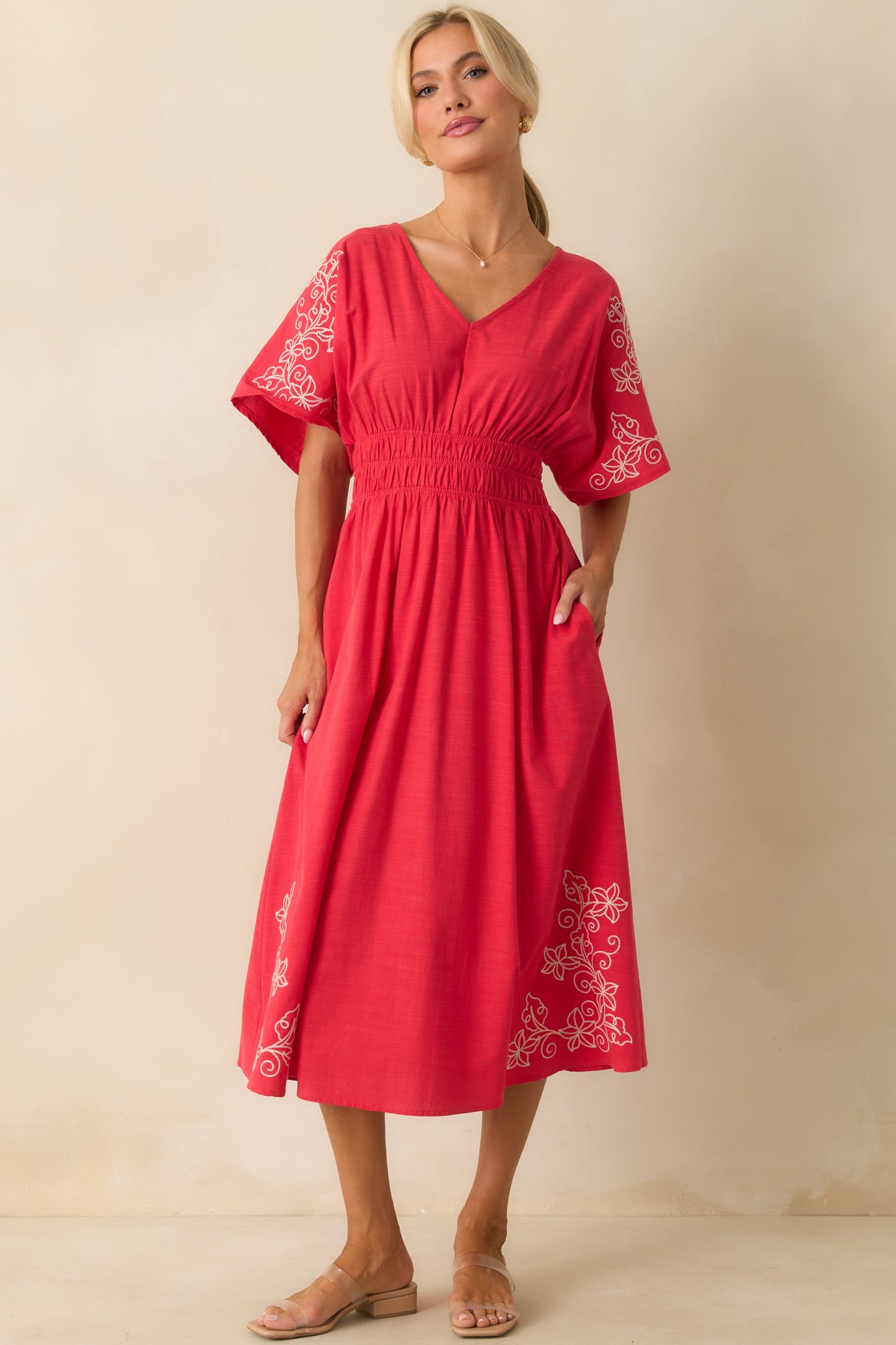 Flowing red dress with floral embroidery, v-neck, and short oversized sleeves.