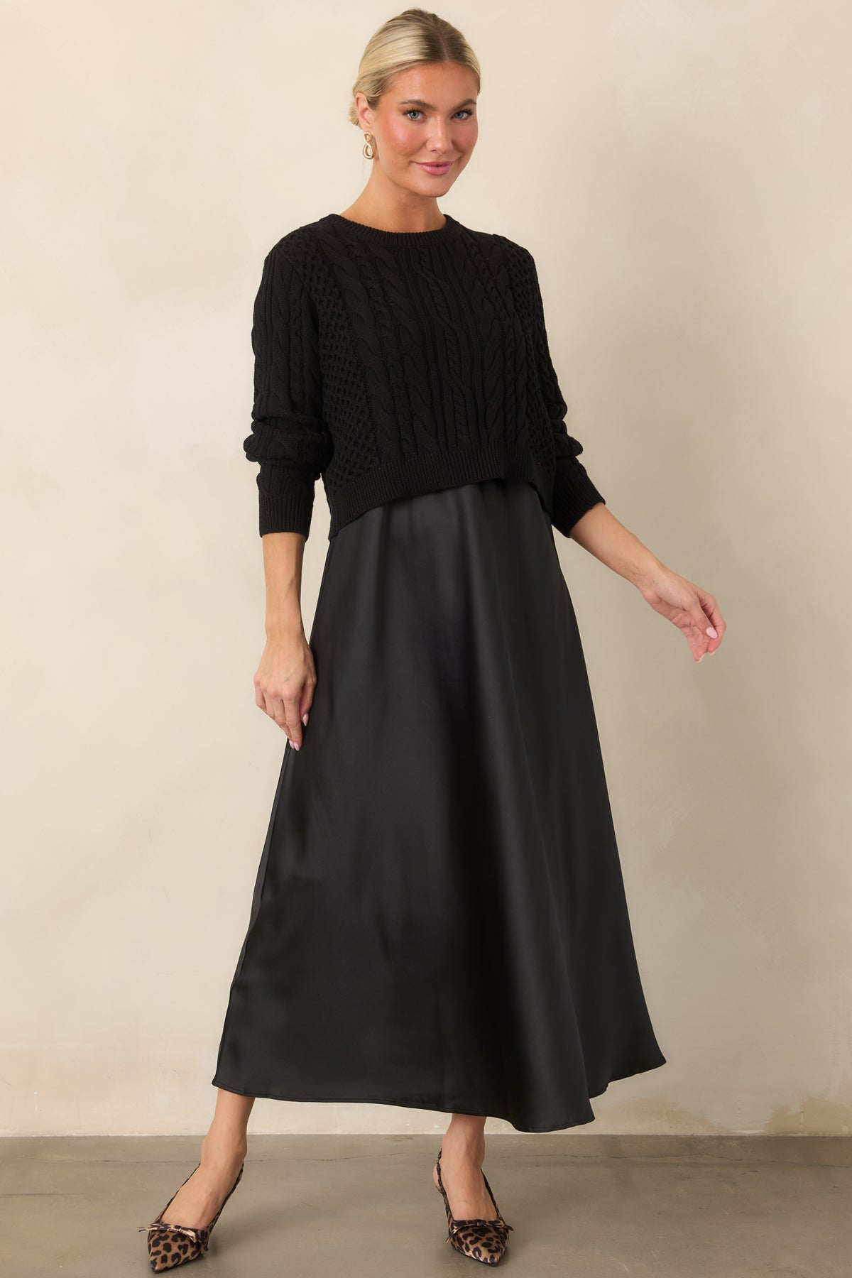 Fluid satin maxi dress showcases an elegant A-line silhouette paired with a richly textured cable-knit sweater.