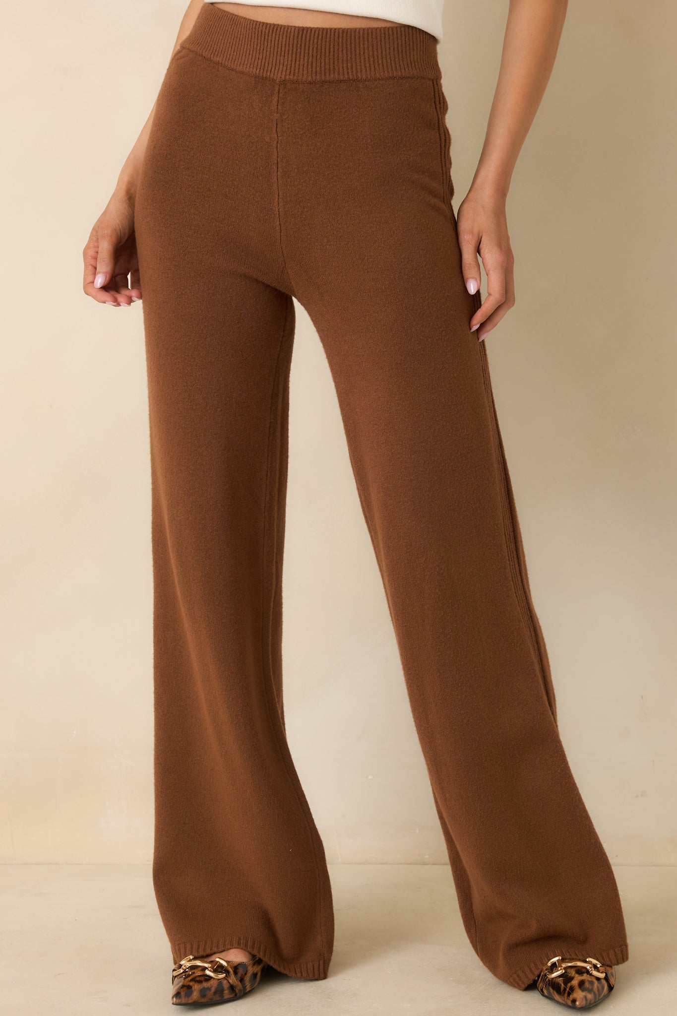 Focused detail of smooth brown fabric with straight-leg silhouette and ribbed accents.