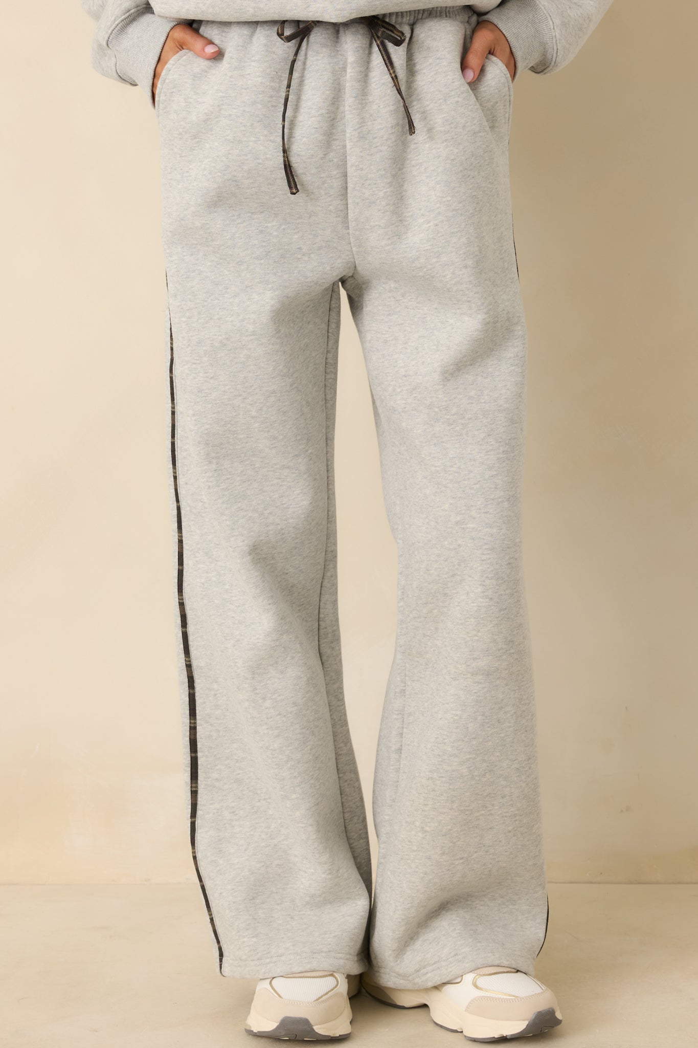 Focused detail of contrast plaid stripe and side pocket on grey pants