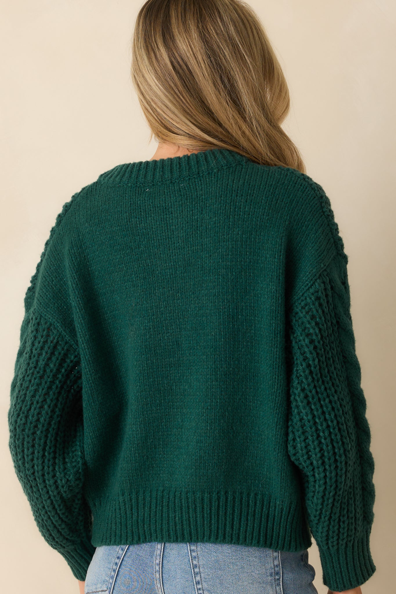 A back view of the forest green cardigan showing the relaxed fit and ribbed hem finish.