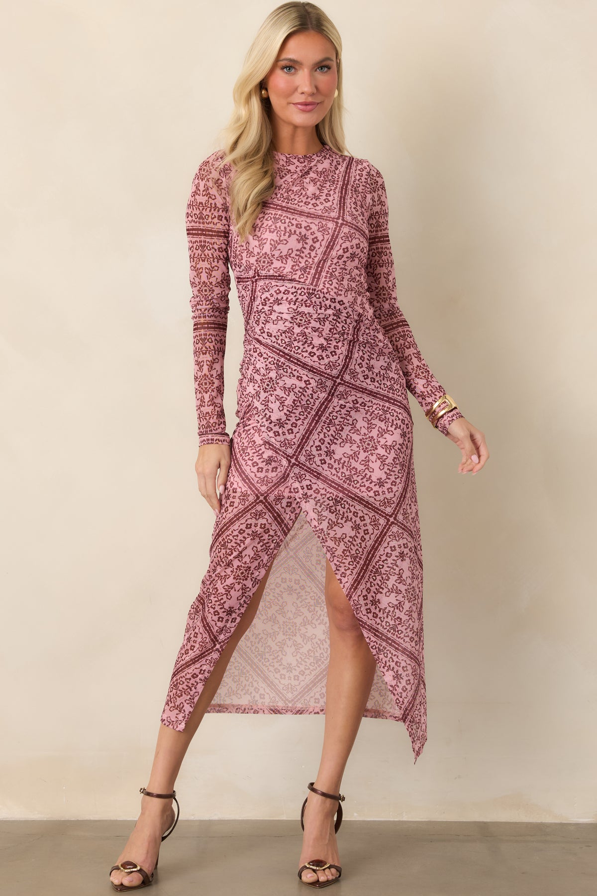 Form-fitting mesh dress designed with a round neckline, ruched waist, sheer sleeves, and a front slit detail.